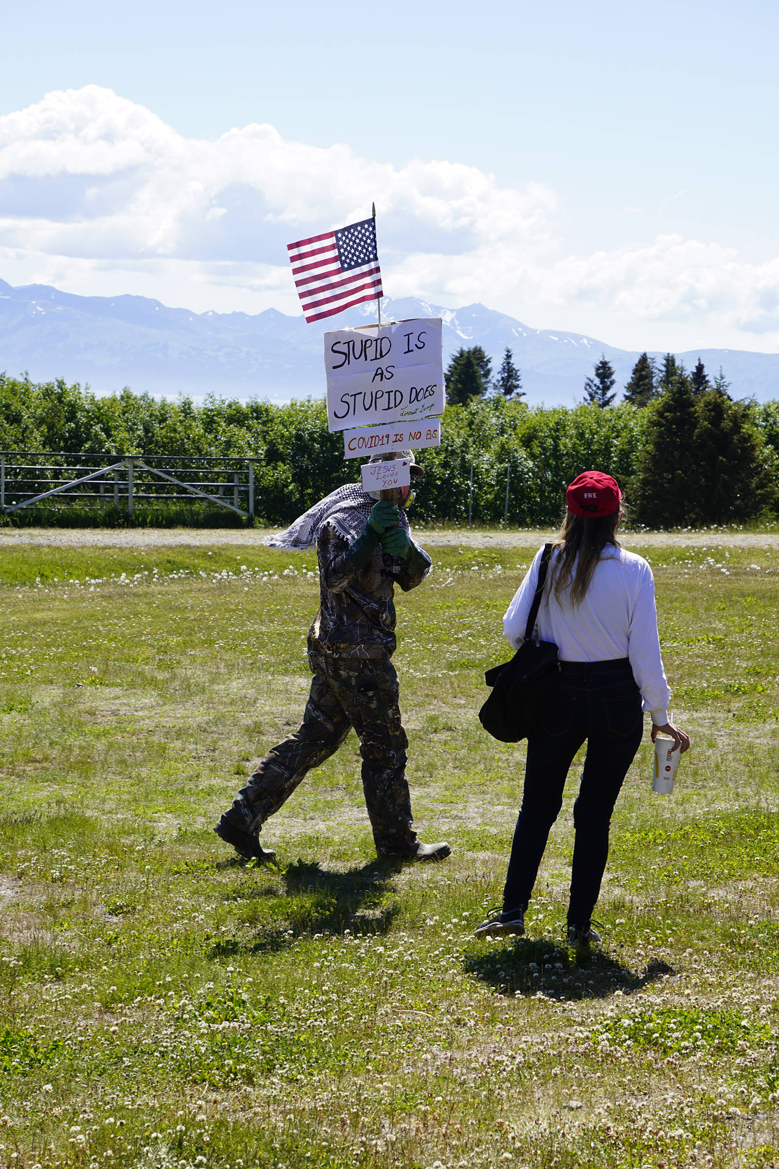 Wearing a respirator, Greg Sutter carries a sign at a campaign rally and ice cream social for Rep. Sarah Vance, R-Homer, on Sunday, June 14, 2020, at Karen Hornaday Park in Homer, Alaska. The sign reads “Stupid is as stupid does - Forrest Gump; COVID-19 is no B.S., and Jesus loves you.” Sutter was the lone protester at Vance’s event. (Photo by Michael Armstrong/Homer News)