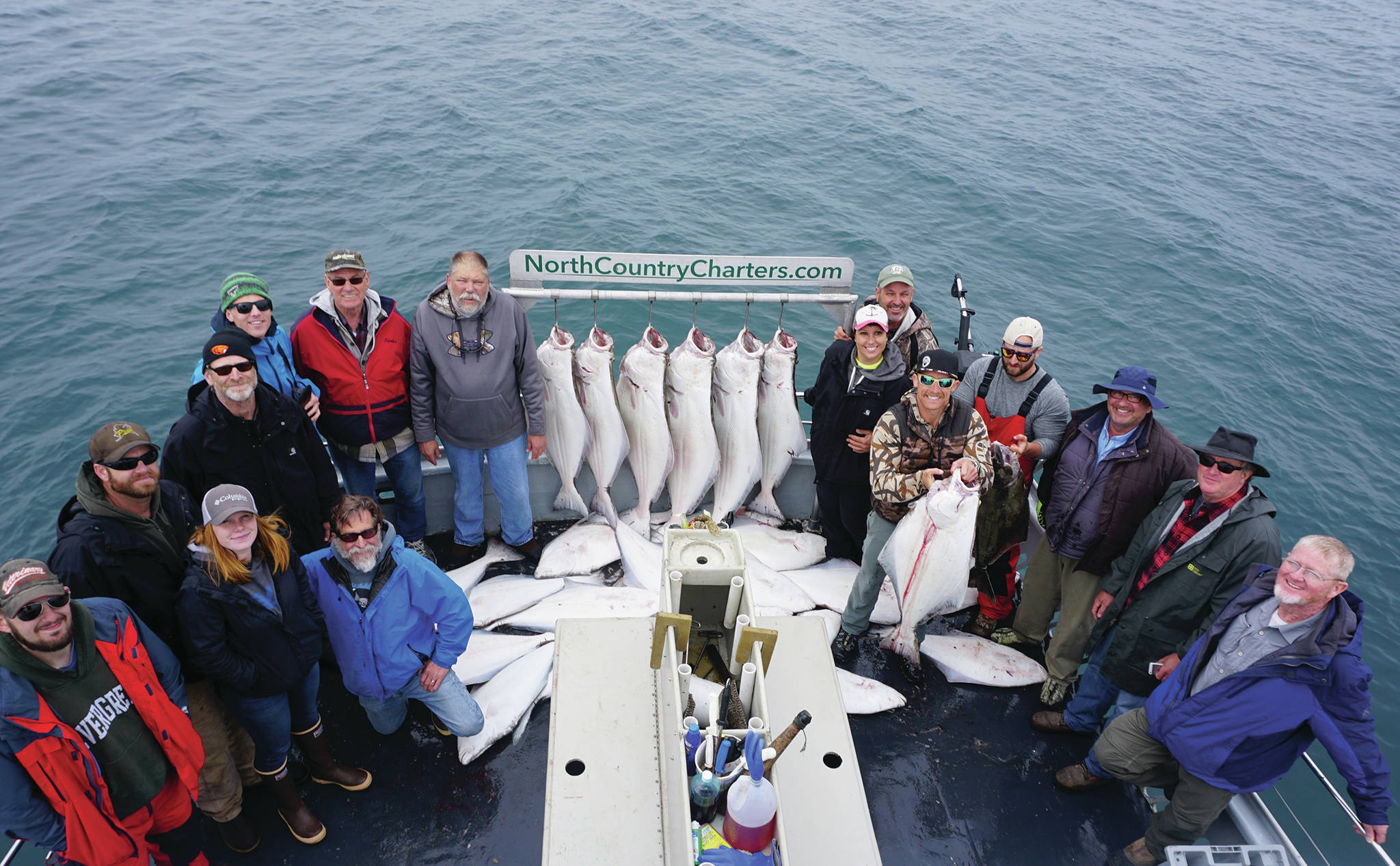 Anglers stand by a rack of halibut on the Irish as the North Country Charters boat returned to Homer in July 2017. (Photo by Michael Armstrong/Homer News file photo)