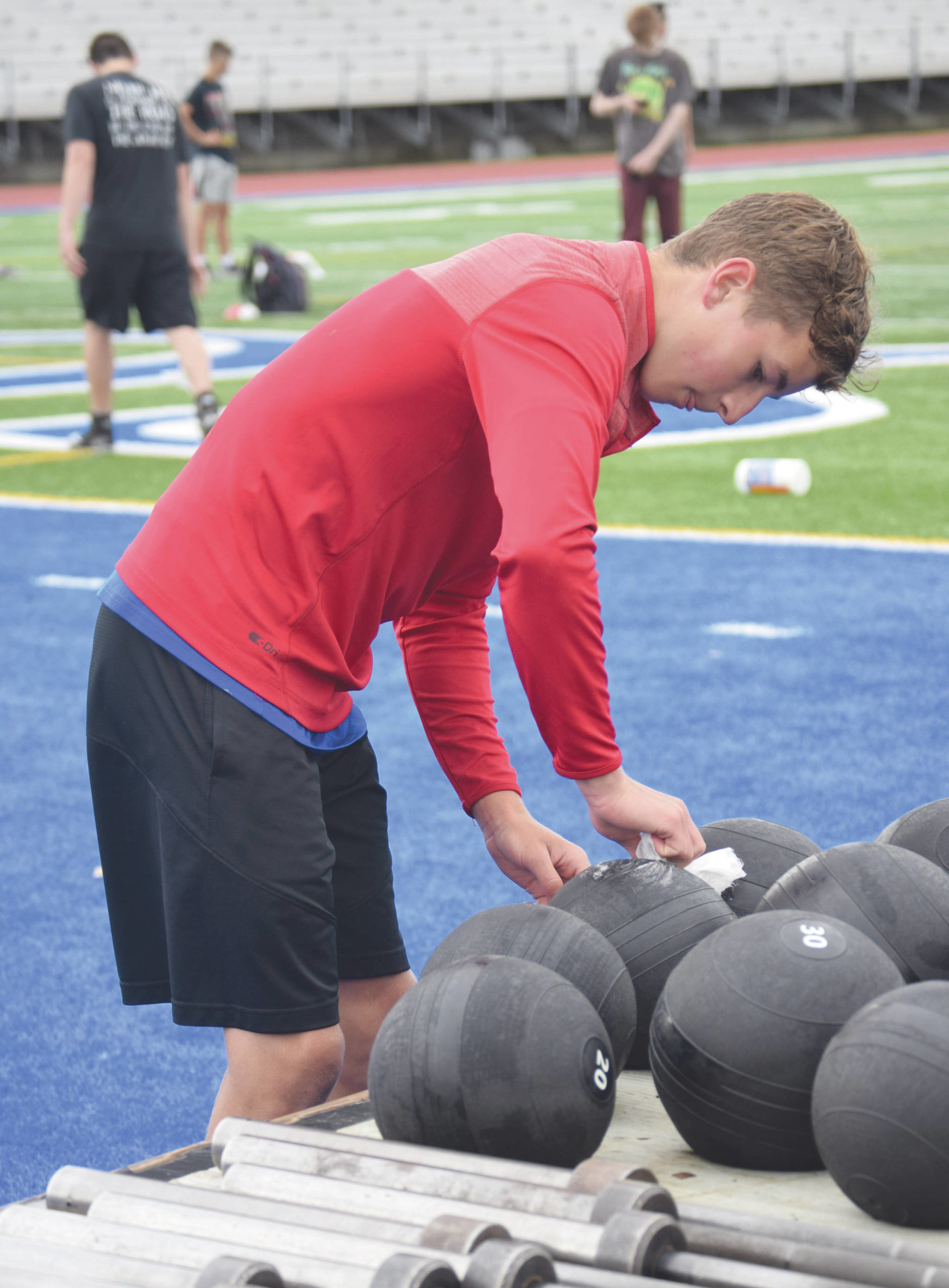 Soldotna football player Zac Buckbee disinfects a smash ball Wednesday, June 17, 2020, at Justin Maile Field in Soldotna, Alaska. (Photo by Jeff Helminiak/Peninsula Clarion)