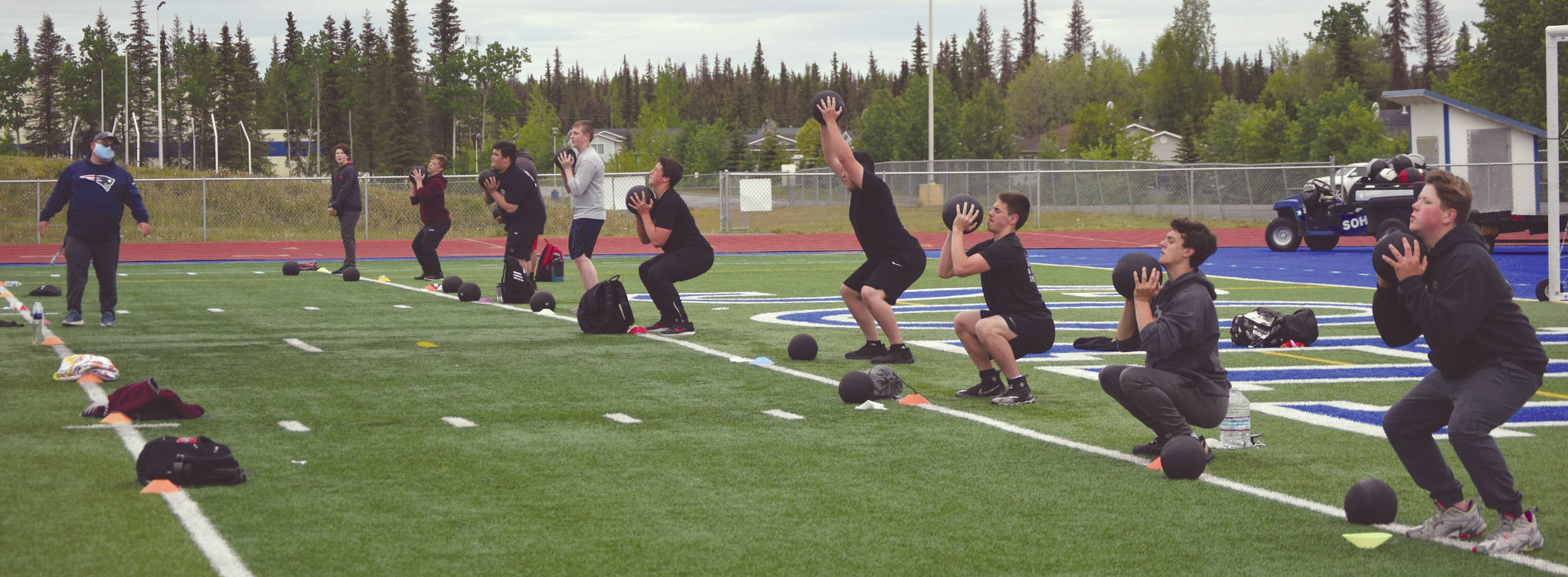 Soldotna assistant football coach Eric Pomerleau leads players through strength and mobility drills Wednesday, June 17, 2020, at Justin Maile Field at Soldotna High School in Soldotna, Alaska. (Photo by Jeff Helminiak/Peninsula Clarion)