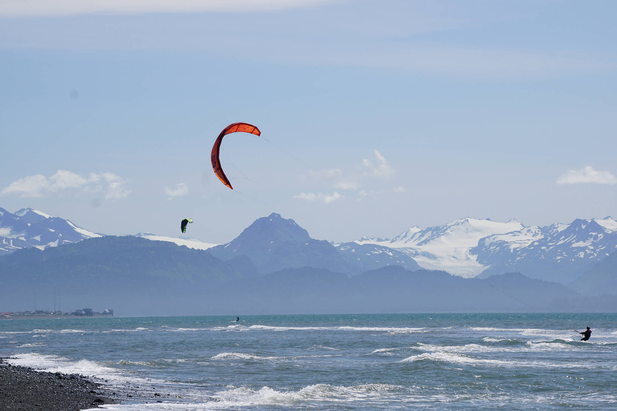 Two kiteboarders play in the wind and surf on Tuesday, June 30, 2020, off the Homer Spit in Homer, Alaska. (Photo by Michael Armstrong/Homer News)