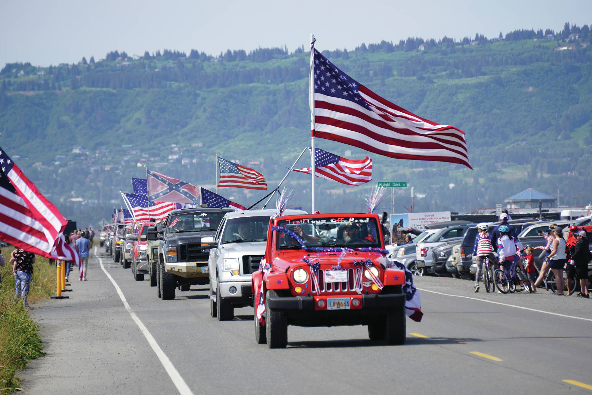Driving a red Jeep, Matthew Mitchell leads an unofficial parade from Soundview Avenue on the Sterling Highway to the end of the Homer Spit on Saturday, July 4, 2020 in Homer, Alaska. Mitchell helped organize the event after the Homer Chamber of Commerce and Visitor Center canceled Homer’s Fourth of July parade. (Photo by Michael Armstrong/Homer News)