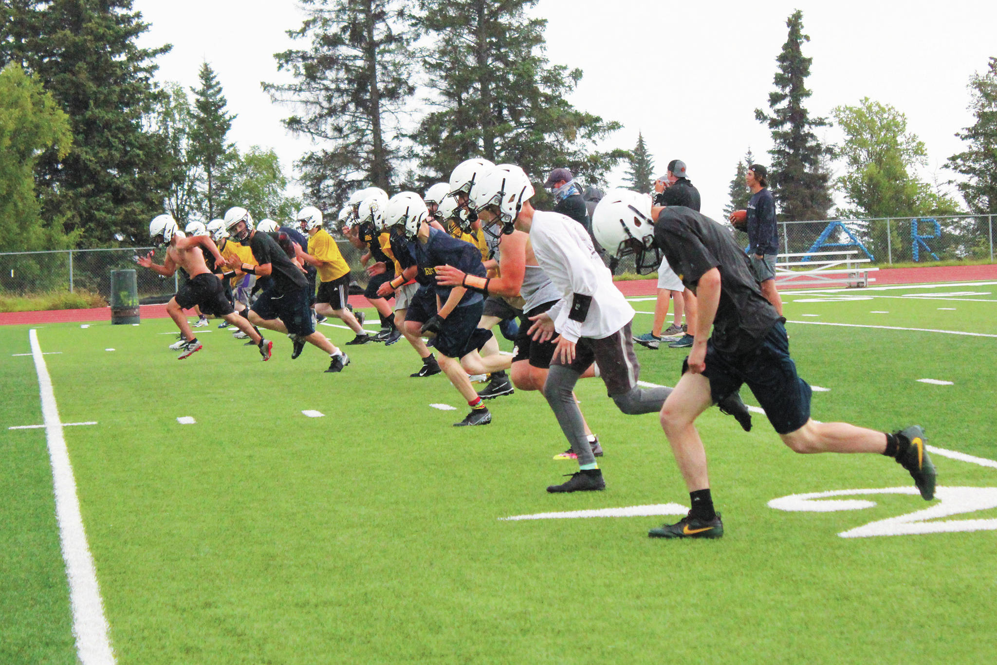 Members of the Homer High School football team complete running drills during a Tuesday, Aug. 18, 2020 practice on the turf field outside the high school in Homer, Alaska. (Photo by Megan Pacer/Homer News)