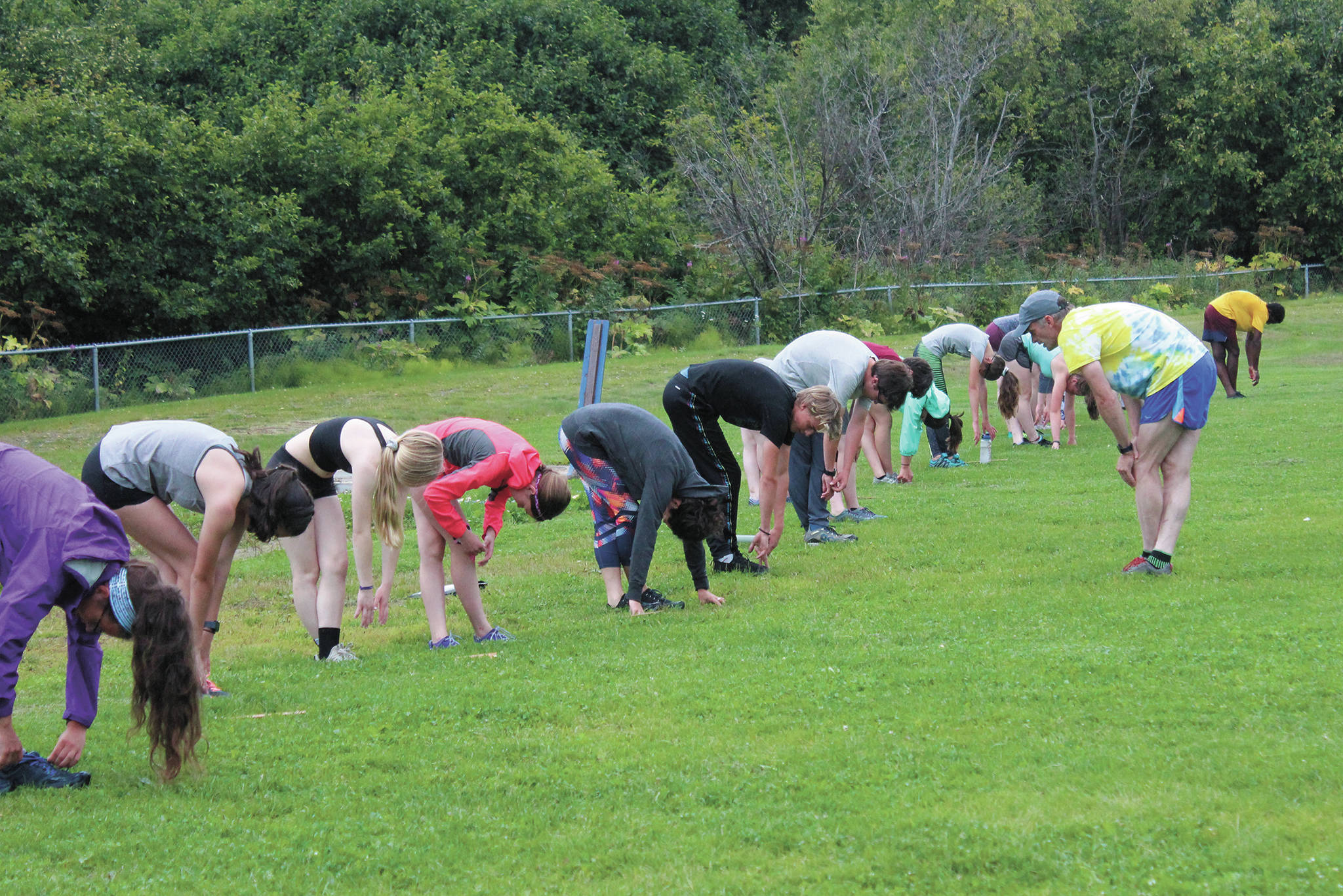 Members of the Homer cross country team stretch with coach Bob Ostrom, right, at the beginning of a Tuesday, Aug. 18, 2020 practice at Homer High School in Homer, Alaska. (Photo by Megan Pacer/Homer News)
