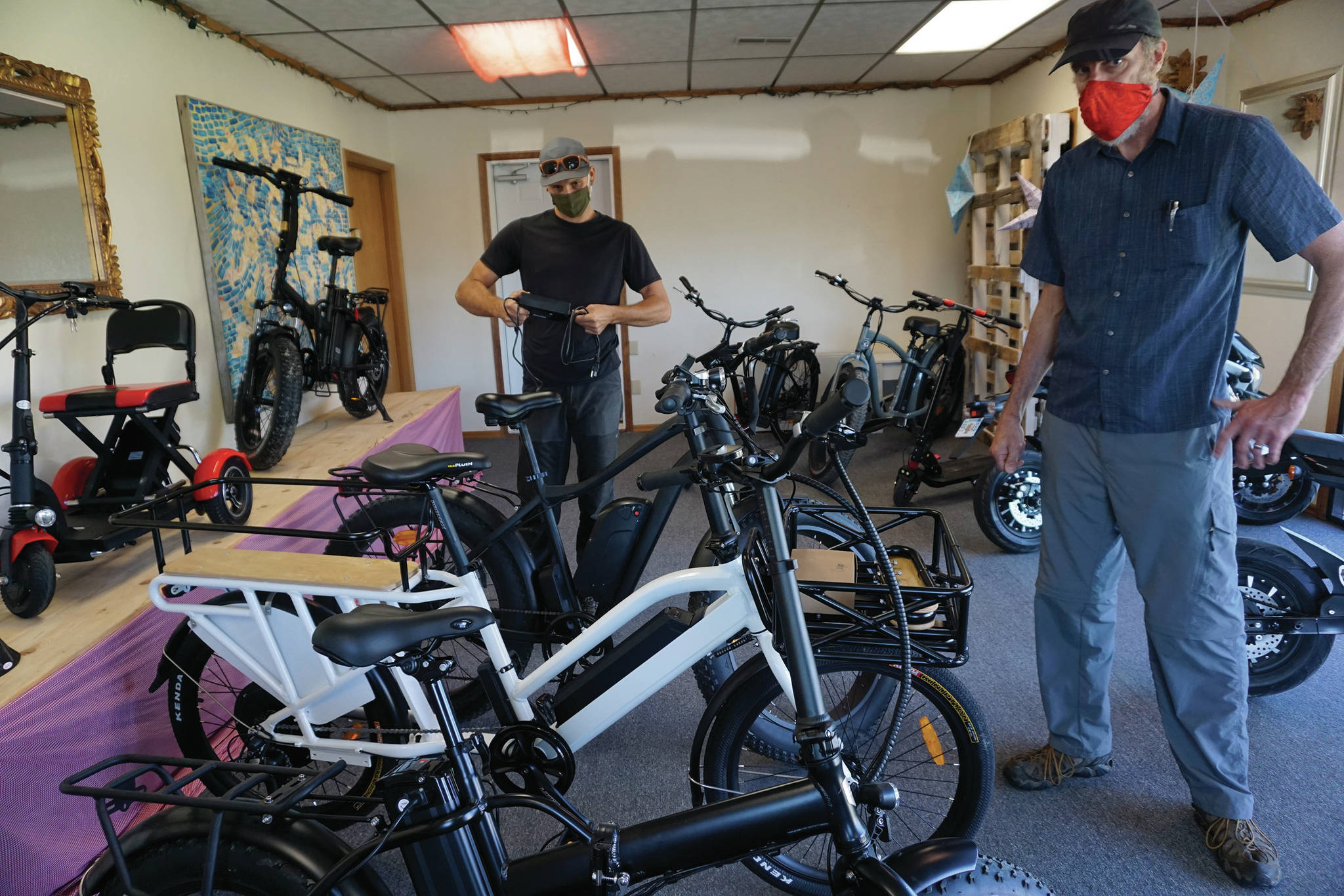 Dale Banks, right, owner of LoopEride, and Chase Warren, right, LoopEride mechanic, display some of the electric-motor assist bicycles at an open house held Friday, Aug. 21, 2020, at the company showroom on East Bunnell Avenue in Homer, Alaska. (Photo by Michael Armstrong/Homer News)
