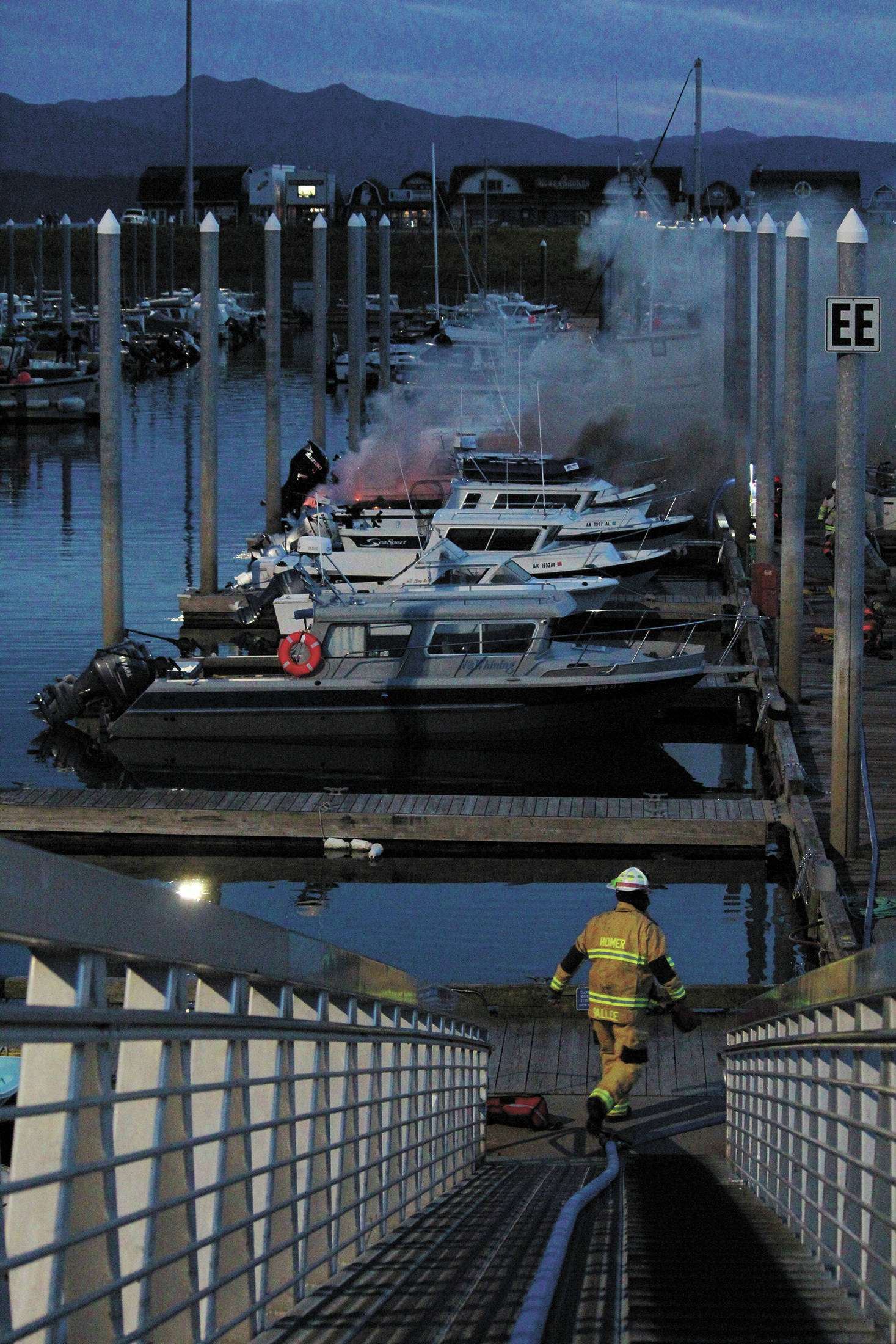 A member of the Homer Volunteer Fire Department walks toward a boat fire on Friday, Sept. 11, 2020 in the Homer Harbor in Homer, Alaska. Firefighters doused the blaze that caught on a 32-foot fiberglass boat that evening. (Photo by Megan Pacer/Homer News)