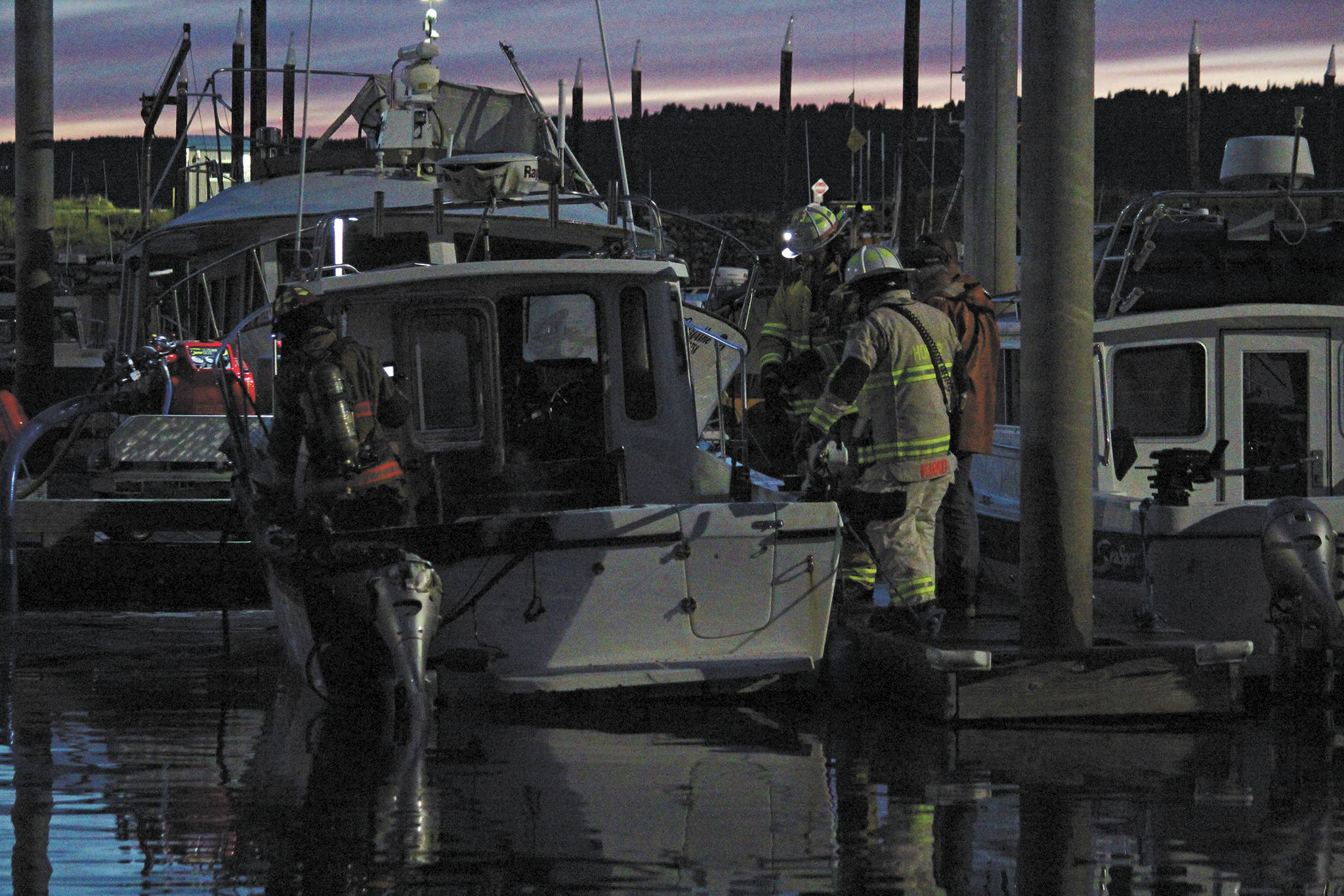 Firefighters finish putting out a fire on a 32-foot fiberglass boat on Friday, Sept. 11, 2020 at the Homer Harbor in Homer, Alaska. No one was onboard at the time and no one was injured. (Photo by Megan Pacer/Homer News)