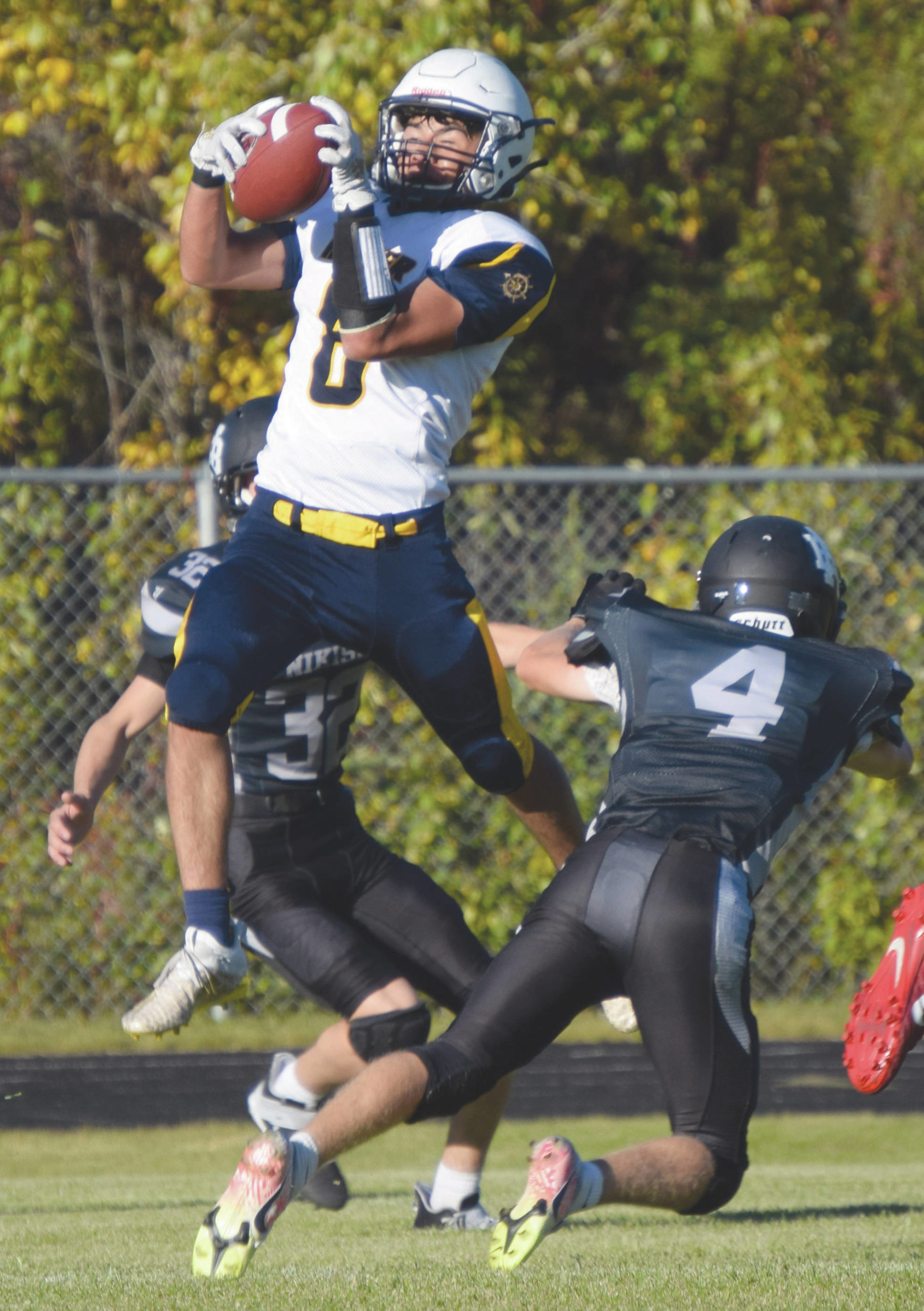 Homer’s Sly Gaona makes a touchdown catch in front of Nikiski’s Jaryn Zoda and Gavin White on Friday, Sept. 11, 2020, at Nikiski High School in Nikiski, Alaska. (Photo by Jeff Helminiak/Peninsula Clarion)