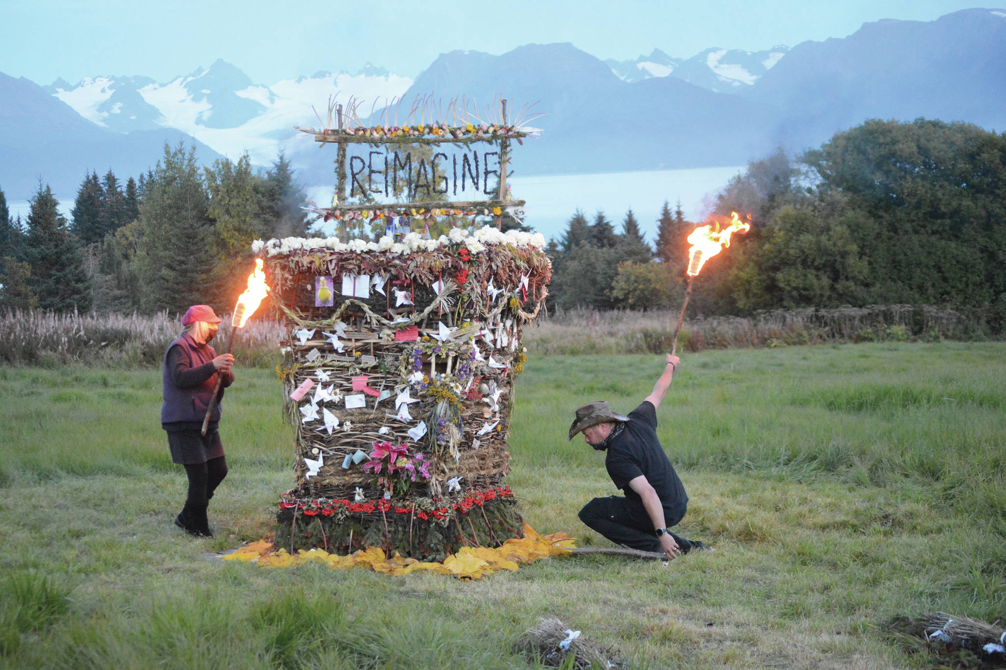 Mavis Muller, left, and Matt Steffy, right, light on fire “Reimagine,” the 17th annual Burning Basket, in a field on Sunday, Sept. 13, 2020, near Homer, Alaska. Artist and coordinator Muller intended to broadcast live on Facebook and YouTube the burning of the basket, but because of technical difficulties that didn’t happen. “Burning Basket teaches how to let go of expectations and accept the present moment,” Muller wrote in a text message. “Technology is fickle. The basket, however, did exactly what it promised to do. It helod our collective burderns, our memorials, our joys, sadness, fear, and dispersed all of our good intentions in a plume of smoke, sparks and flames.” (Photo by Michael Armstrong/Homer News)