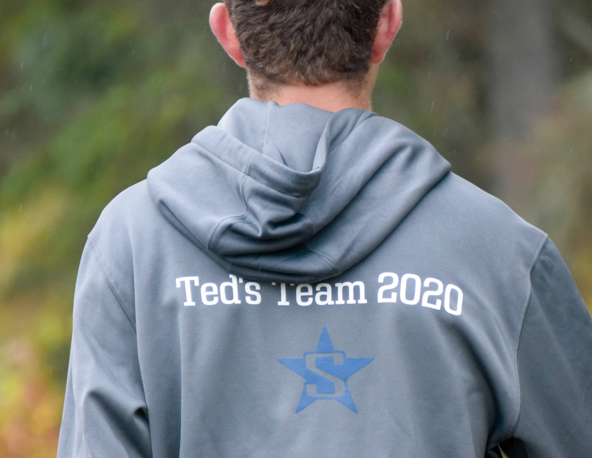 A Soldotna runner wears the team sweatshirt in honor of Ted McKenney, the team’s former coach who died of brain cancer this summer, at the Kenai Peninsula Borough cross-country meet Saturday, Sept. 26, 2020, at Tsalteshi Trails just outside of Soldotna, Alaska. (Photo by Jeff Helminiak/Peninsula Clarion)
