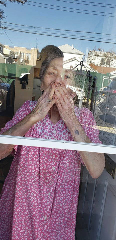 “Kisses Through the Window,” a photo taken by Jamee Schleifer on May 5, 2020, in Brooklyn, New York, of her grandmother, Joyce Arberman, is one of the images submitted to Christina Whiting’s “Behind the Mask - Our Stories” project. (Photo by Jamee Schleifer; courtesy Christina Whiting)