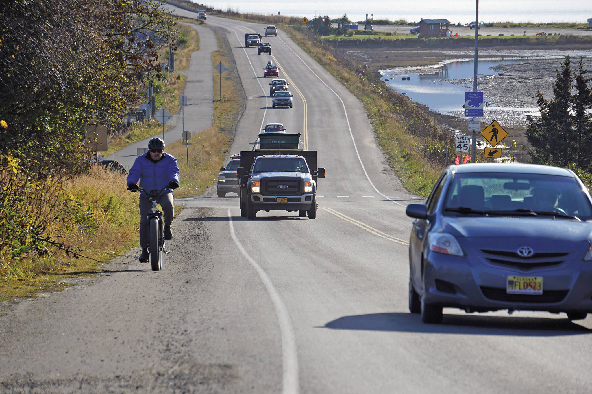A biker leads a line of cars driving off the Homer Spit at about 1:30 p.m. Monday, Oct. 19, 2020, in Homer, Alaska after a tsunami evacuation order was issued for low-lying areas in Homer. (Photo by Michael Armstrong/Homer New)
