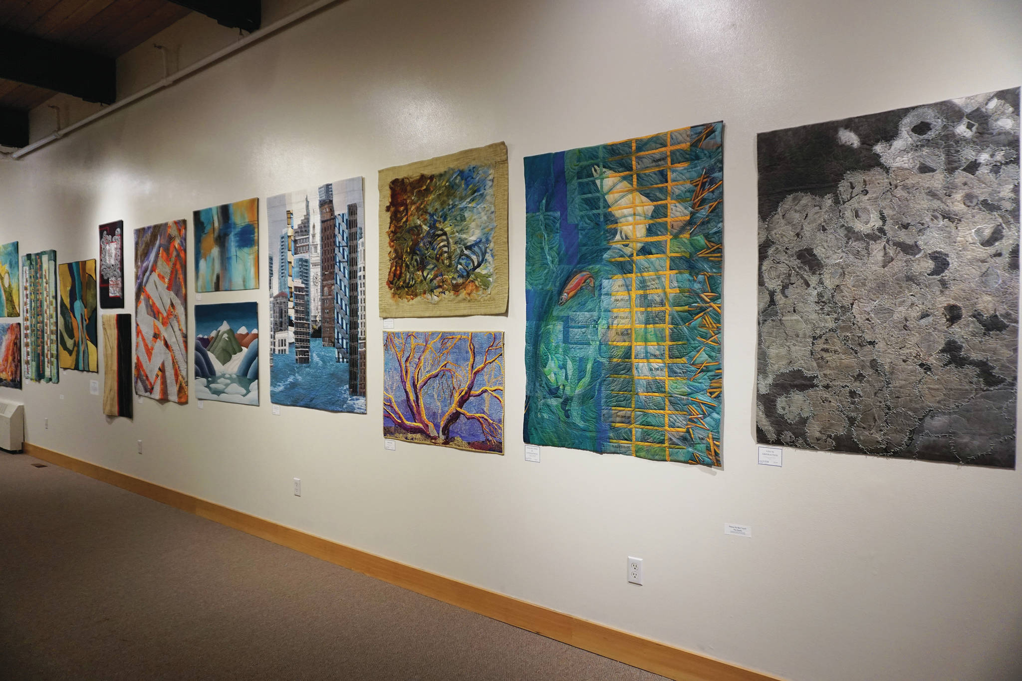 Some of the 45 art quilts featured in “Shifting Tides: Cloth in Convergence,” on exhibit from Oct. 9 to Nov. 28, 2020, at the Pratt Museum in Homer, Alaska. (Photo by Michael Armstrong/Homer News)