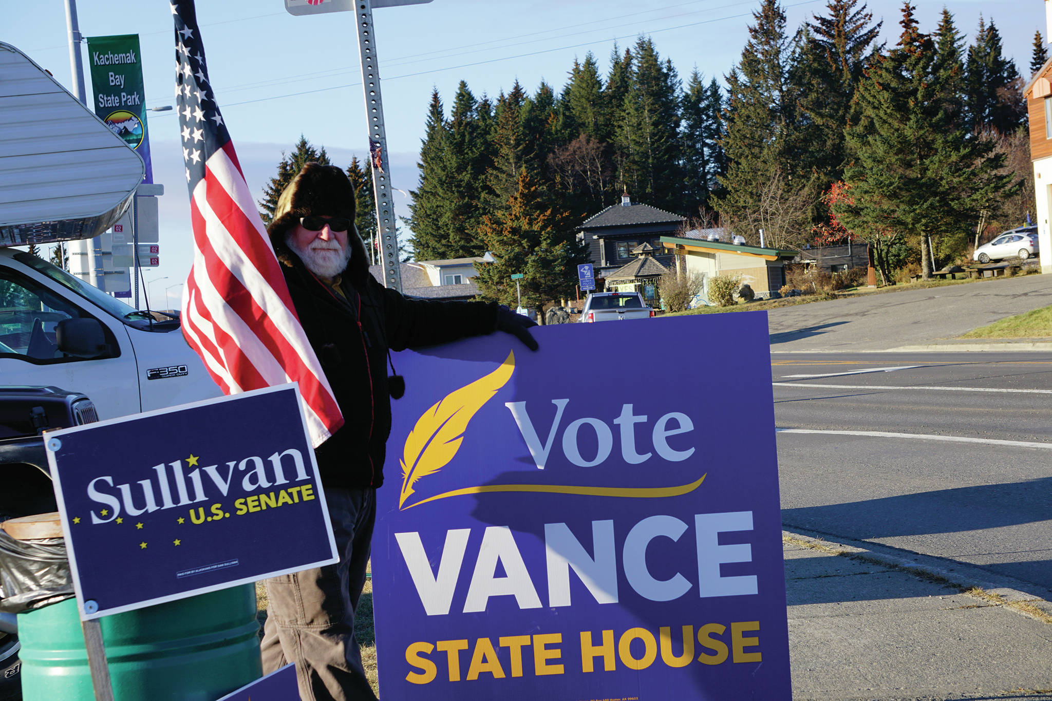 Raymond Walker holds a sign on Tuesday, Nov. 3, 2020, for his daughter, Sarah Vance, on Pioneer Avenue in Homer, Alaska. A Republican, Vance is running for reelection for District 31 Representative in the Alaska Legislature against Independent Kelly Cooper. Walker also holds a sign for Sen. Dan Sullivan, R-Alaska, who is running for reelection to the U.S. Senate. (Photo by Michael Armstrong/Homer News)