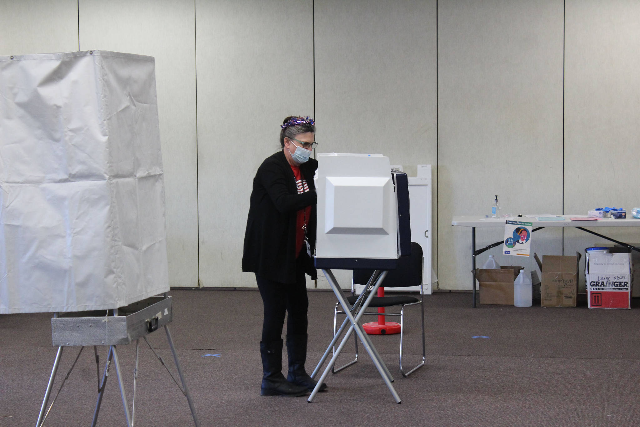 A poll worker disinfects a voting booth at the Soldotna Regional Sports Complex on Tuesday, Nov. 3 in Soldotna, Alaska. (Photo by Ashlyn O’Hara/Peninsula Clarion)