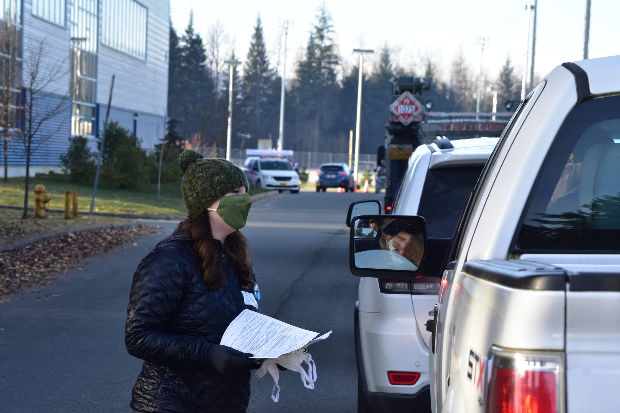 Cindy Carte, a volunteer worker from Bartlett Regional Hospital, hands out paperwork to Juneau residents waiting in line for a drive-thru flu shot clinic at Thunder Mountain High School on Saturday, Oct. 24, 2020. State and city health officials said the October vaccine clinic doubled as a practice run for an eventual coronavirus vaccine distribution. (Peter Segall / Juneau Empire)