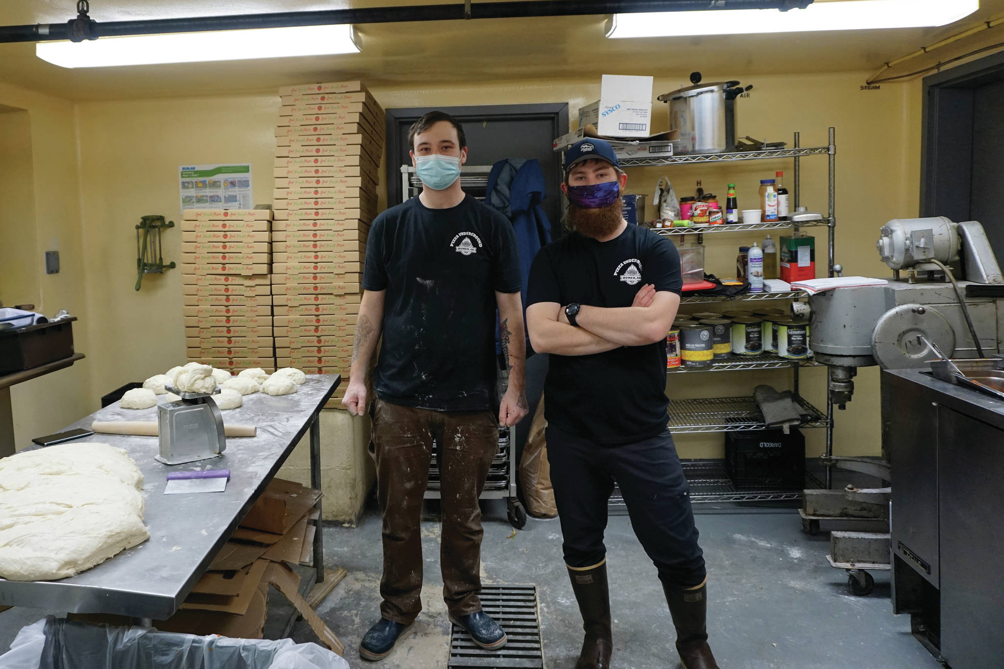 Pizza Underground owner Ethan Eutsler, right, and coworker Jack Pierre, left, take a break from making pizza dough on Tuesday, Dec. 1, 2020, the opening day of the business, in the basement of Alice’s Champagne Palace in Homer, Alaska. (Photo by Michael Armstrong/Homer News)