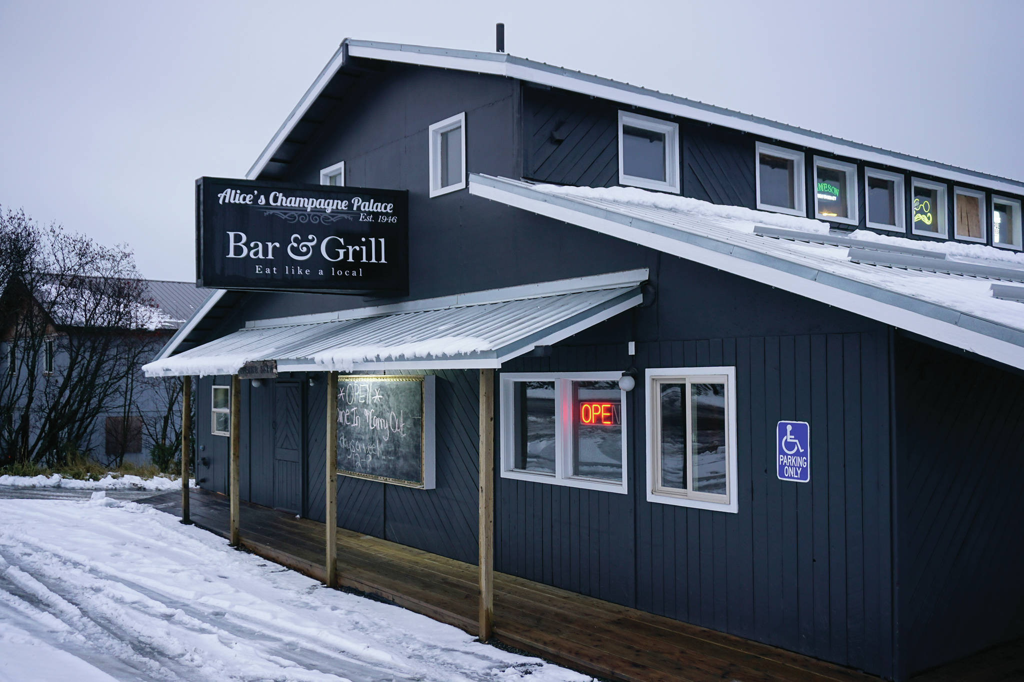 Rain and snow fall on Alice’s Champagne Palace on Tuesday, Dec. 1, 2020, in Homer, Alaska. The iconic bar on Pioneer Avenue is the site of Pizza Underground, located in the basement. (Photo by Michael Armstrong/Homer News)