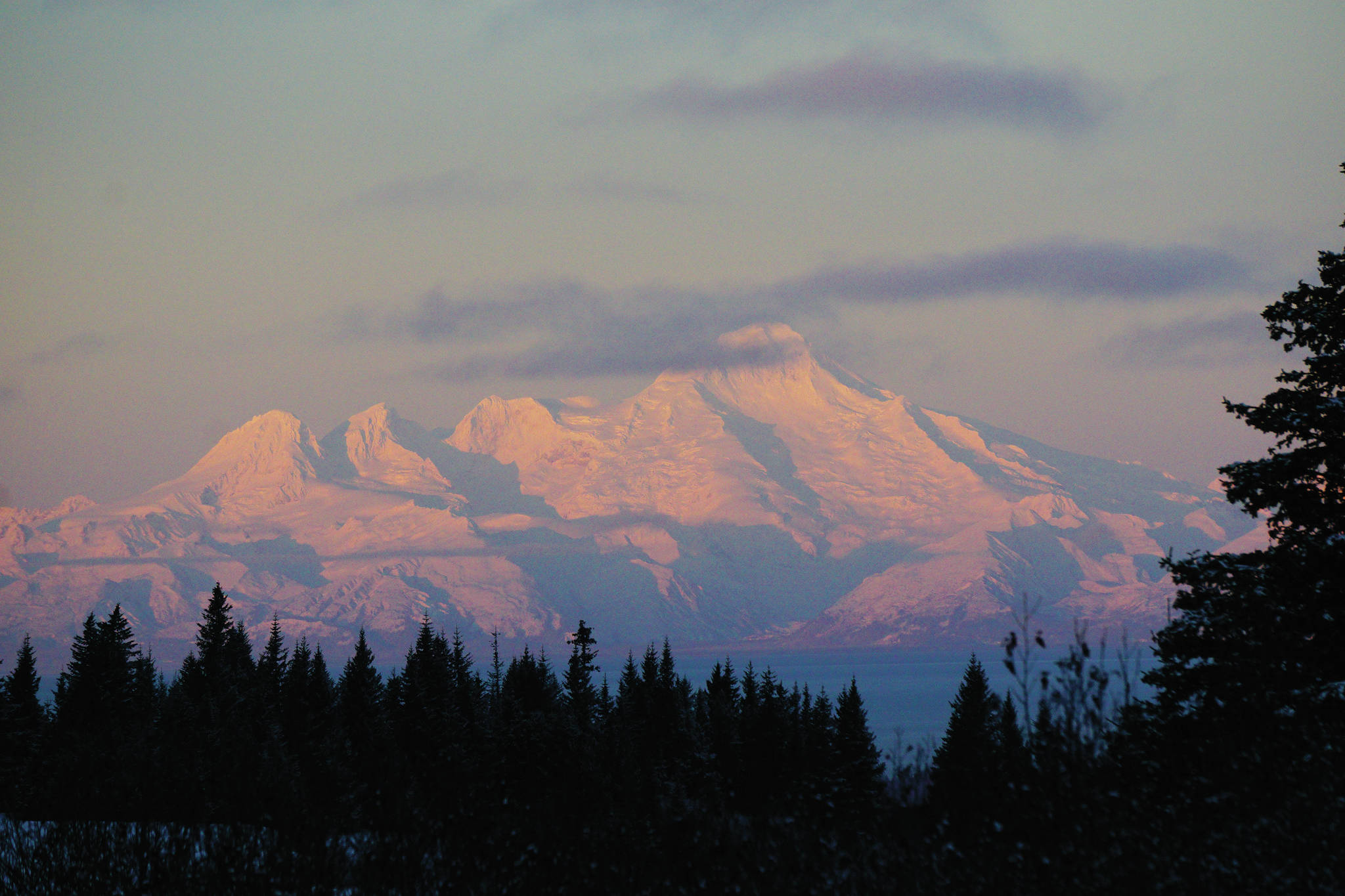 Mount Iliamna glows pink as the sun rises on Wednesday morning, Dec. 16, 2020, as seen from Diamond Ridge near Homer, Alaska. Iliamna is one of three Cook Inlet volcanoes visible from Homer. (Photo by Michael Armstrong/Homer News)