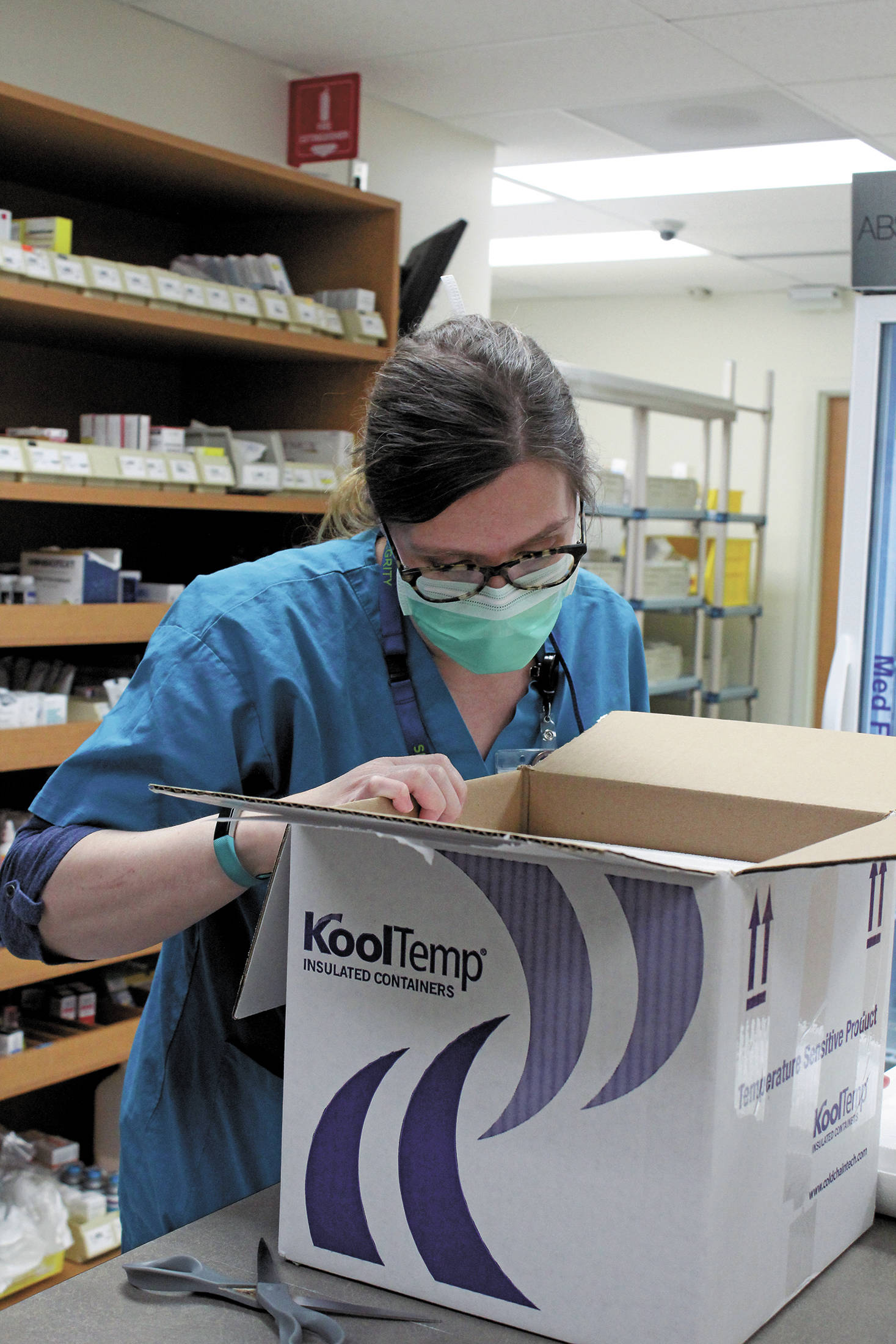 South Peninsula Pharmacist Jill Kort peers into a box filled with 180 doses of the Pfizer vaccine for COVID-19 shortly after it arrived at the hospital on Wednesday, Dec. 16, 2020 in Homer, Alaska. (Photo by Megan Pacer/Homer News)