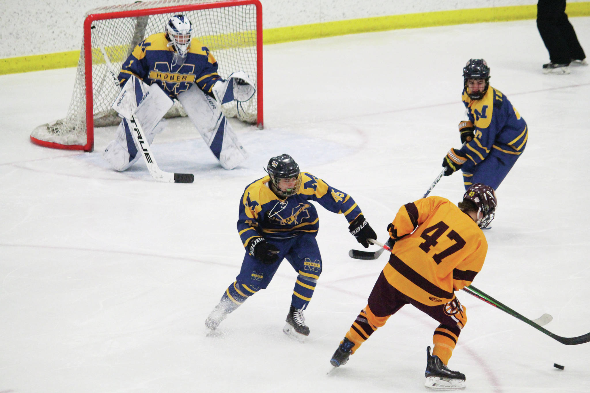 Homer’s Bergen Knutson (left) and Toby Nevak (right) try to fend off Dimond’s Kaden Daniels during a Friday, Feb. 14, 2020 game at the 2020 ASAA First National Cup Division I Hockey State Championship at the Curtis D. Menard Memorial Sports Center in Wasilla, Alaska. (Photo by Megan Pacer/Homer News)