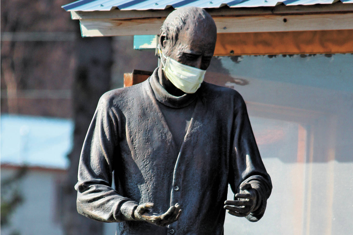 The statue of Brother Asaiah Bates that stands at Cosmic Kitchen is seen wearing a mask on Monday, April 6, 2020 in Homer, Alaska. The state of Alaska is currently advising people to wear protective cloth coverings when they have to go out in public for essentials. (Photo by Megan Pacer/Homer News)