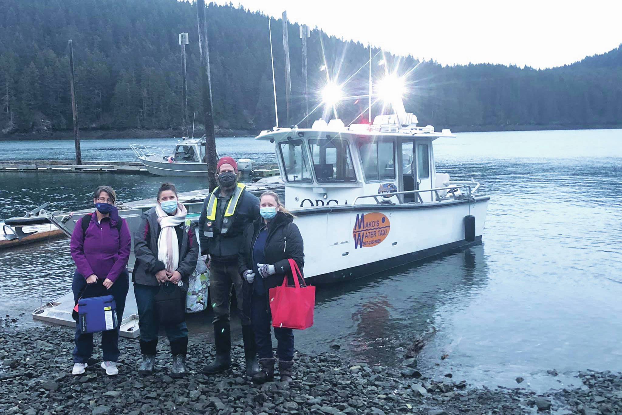 Curtis Jackson, second from right, poses on Thursday, Dec. 17, 2020, with SVT Health & Wellness Center health care workers in Jakolof Bay, Alaska, after making a trip across Kachemak Bay from Homer to deliver the medical team and Pfizer COVID-19 vaccine. From left to right are nurse Candice Kreger, family nurse practitioner Kourtney Holder, Jackson, and family nurse practitioner Julie Drude. The health care workers then went by road to Seldovia. (Photo by Janel Harris courtesy of Mako’s Water Taxi)