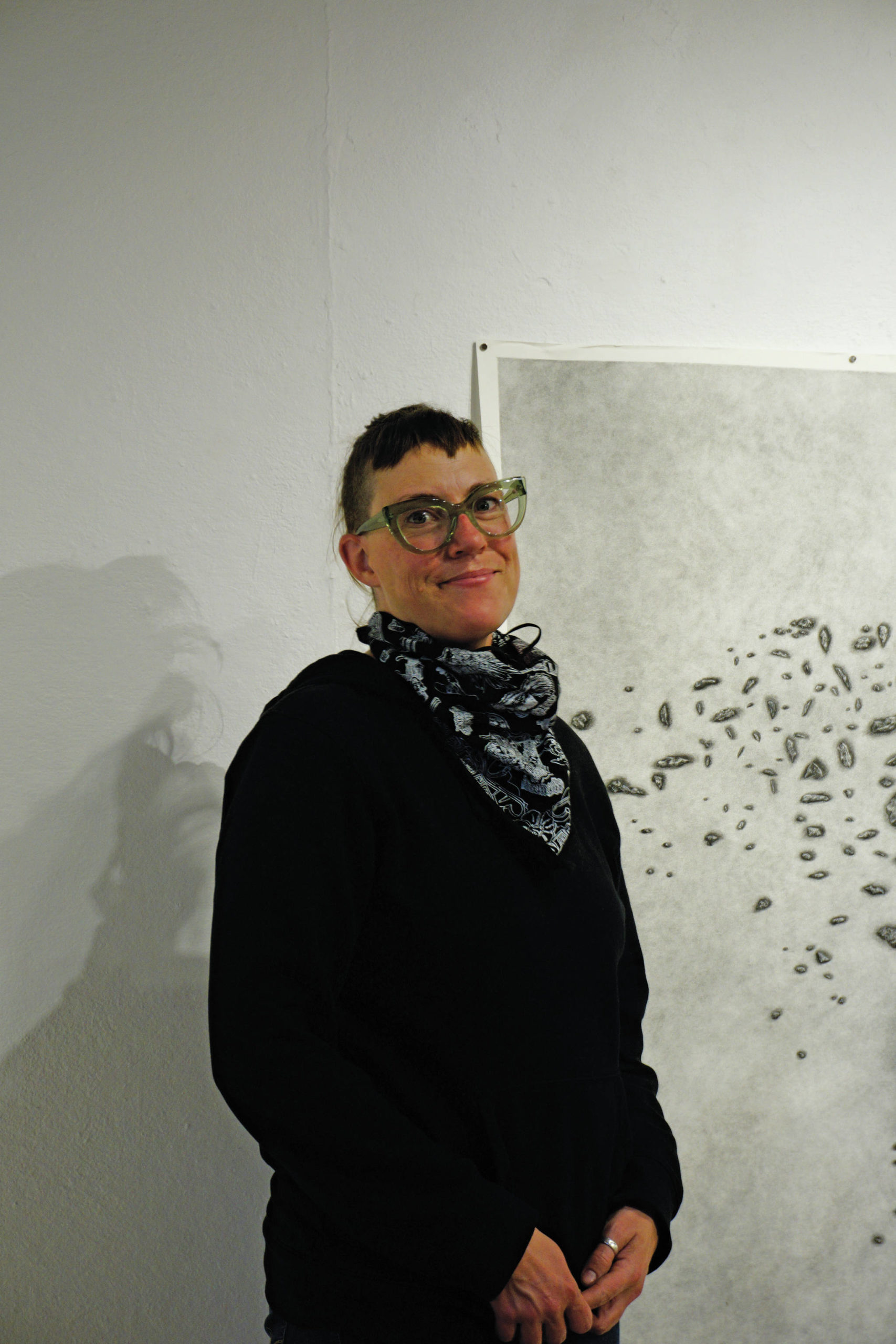On Thursday, Feb. 11, 2021, in Homer, Alaska, Bunnell Street Arts Center Artist in Residence Nina Elder stands next to a drawing from her series, “It Will Not Be the Same, But It Might Be Beautiful,” drawings of puzzle stones collected in the area near McCarthy, Alaska. (Photo by Michael Armstrong/Homer News)