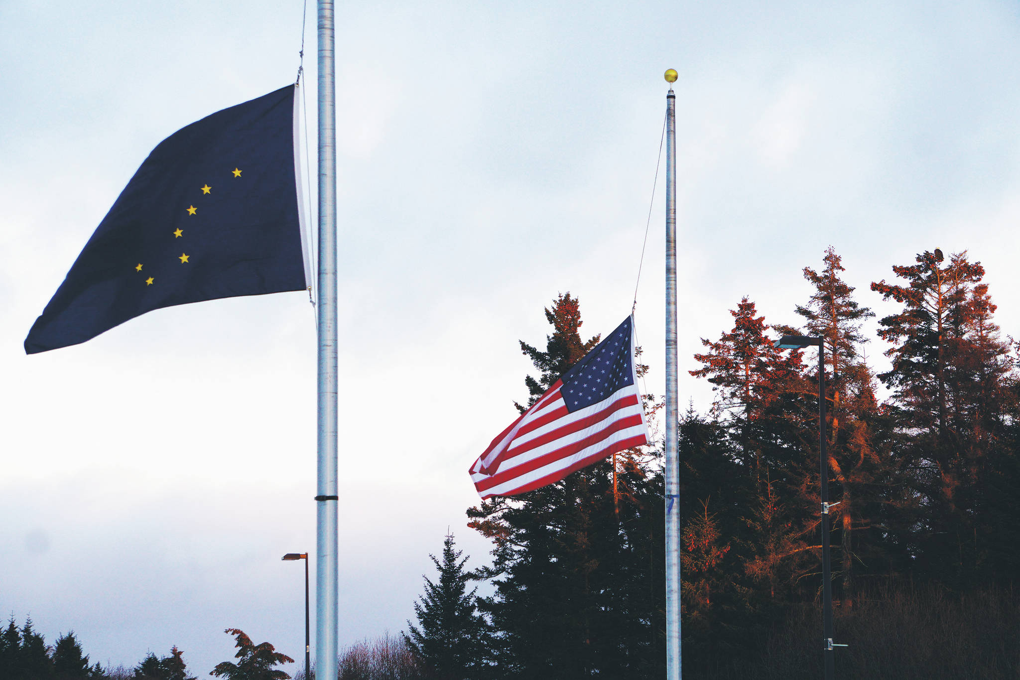 The Alaska and U.S. flags fly at half staff on Monday, Feb. 22, 2021, at the Alaska Islands and Ocean Visitor Center in Homer, Alaska. President Joe Biden on Monday ordered flags to be flown at half staff at federal facilities for five days to honor the 500,000 Americans who have died of COVID-19. (Photo by Michael Armstrong/Homer News)