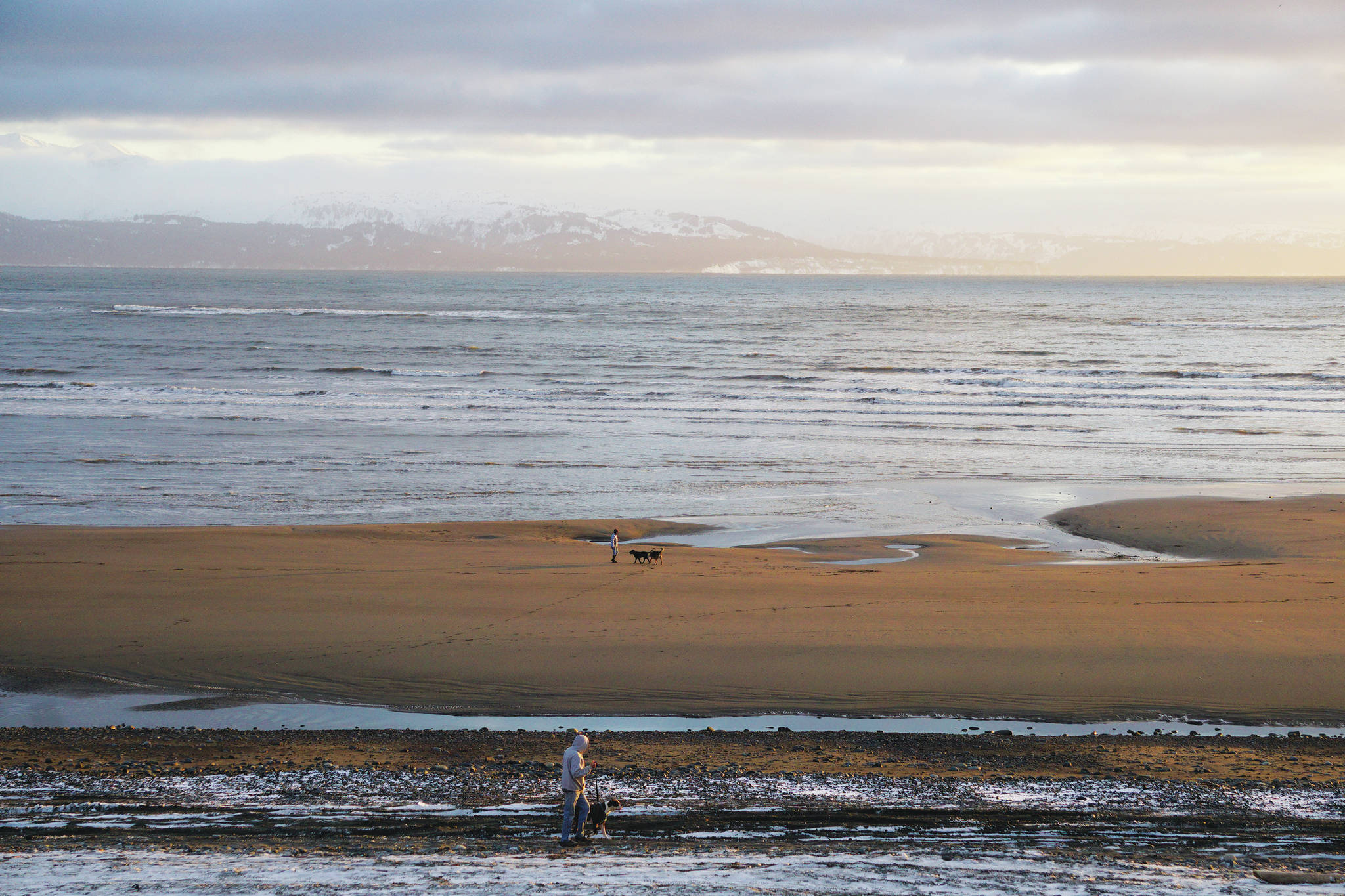 People walk their dogs at sunset on Monday, Feb. 22, 2021, at Bishop’s Beach in Homer, Alaska. (Photo by Michael Armstrong/Homer News)