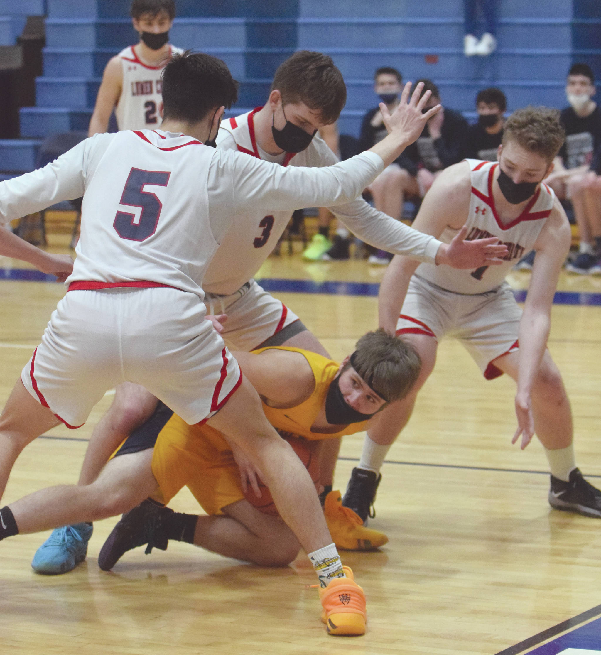Ninilchik’s Cole Hadro is surrounded by Noah Cruz, Daniel Bennett and Tim Bennett of Lumen Christi on Friday, March 19, 2021, in the Peninsula Conference championship game at Soldotna High School in Soldotna, Alaska. (Photo by Jeff Helminiak/Peninsula Clarion)