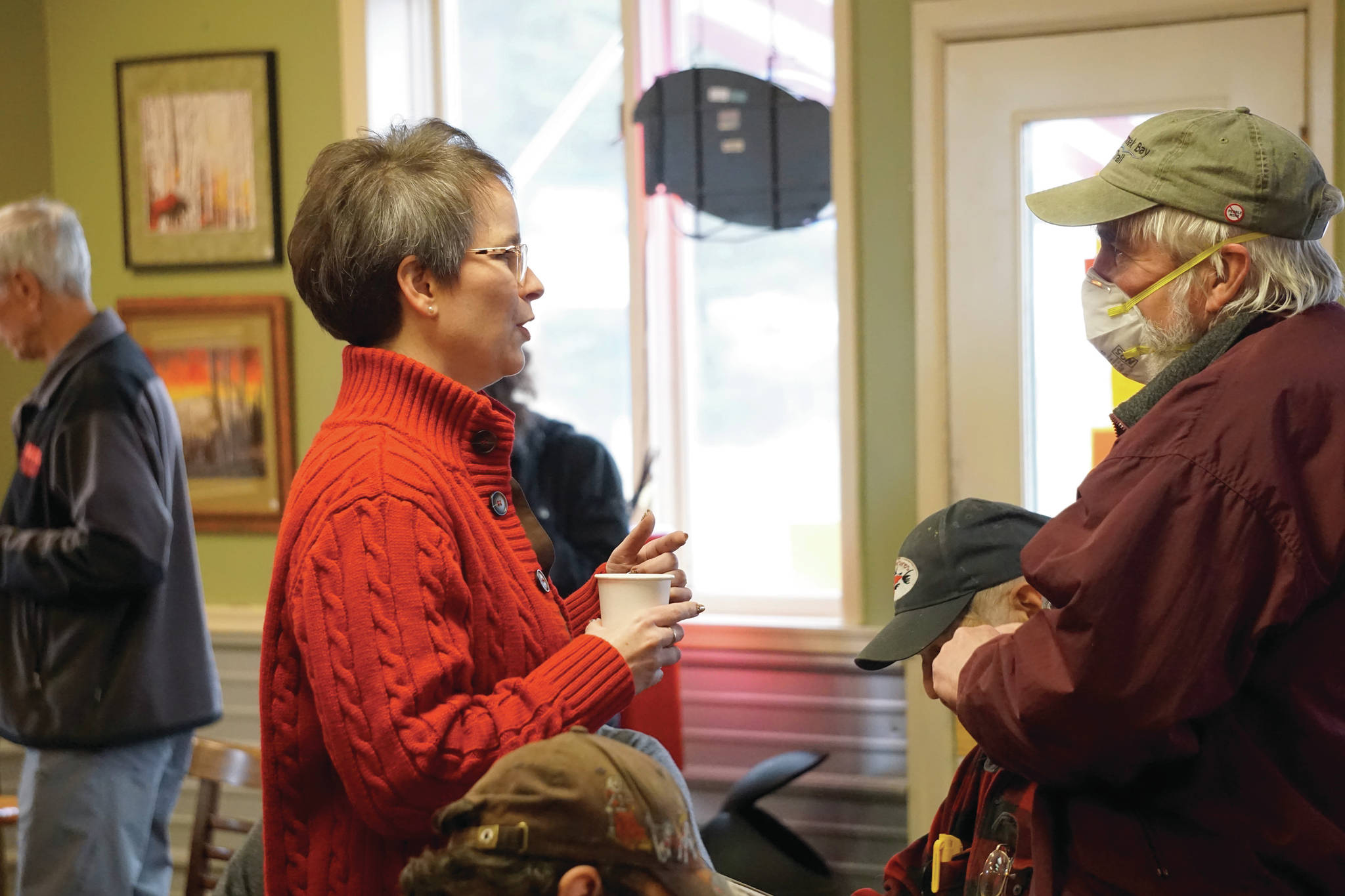 Rep. Sarah Vance, R-Homer, left, speaks with Robert Archibald, right, before holding a town hall meeting on Monday, March 29, 2021, at Captain’s Coffee in Homer, Alaska. Archibald was only one of four people who wore face masks at the event of about 55 people. (Photo by Michael Armstrong/Homer News)