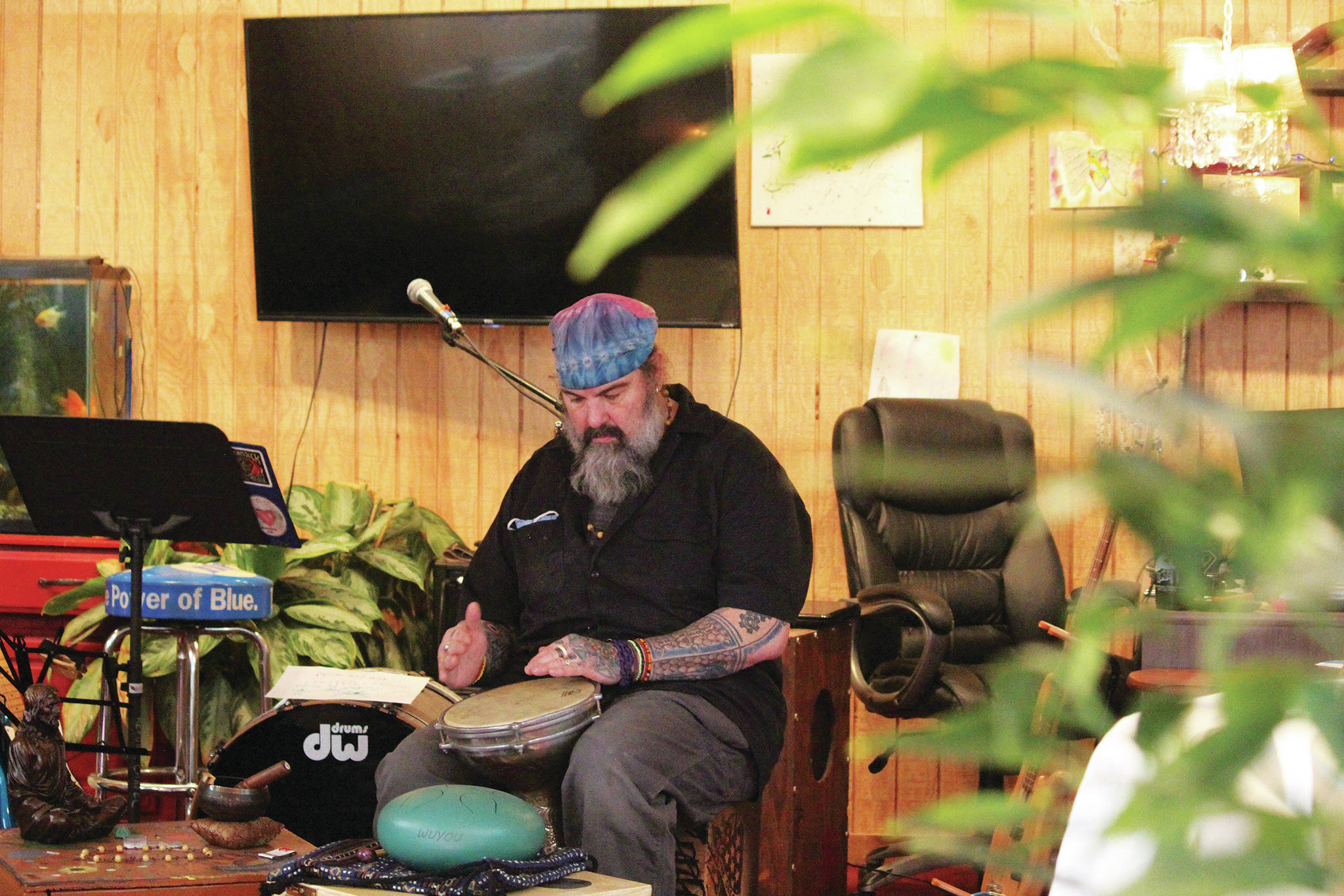 Darren Williams, owner of the Plant Man, plays a drum in his newly expanded space in the Wildberry Building on Pioneer Avenue on Feb. 19, 2021 in Homer, Alaska. (Photo by Megan Pacer/Homer News)