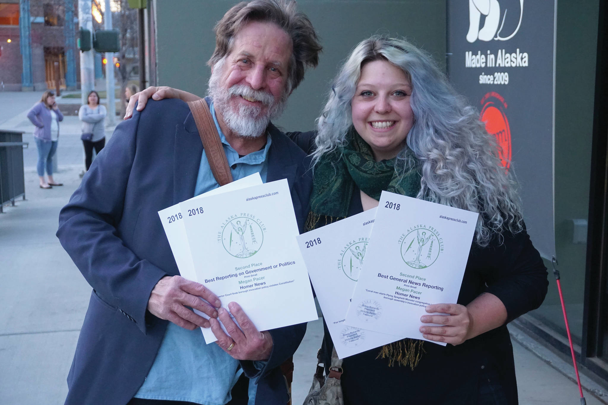 Homer News editor Michael Armstrong, left, and fomer reporter Megan Pacer, right, hold Alaska Press Club awards the Homer News received at the Alaska Press Club Awards banquet on April 27, 2019, in Anchorage, Alaska. (Photo by Brian Mazurek/Peninsula Clarion)