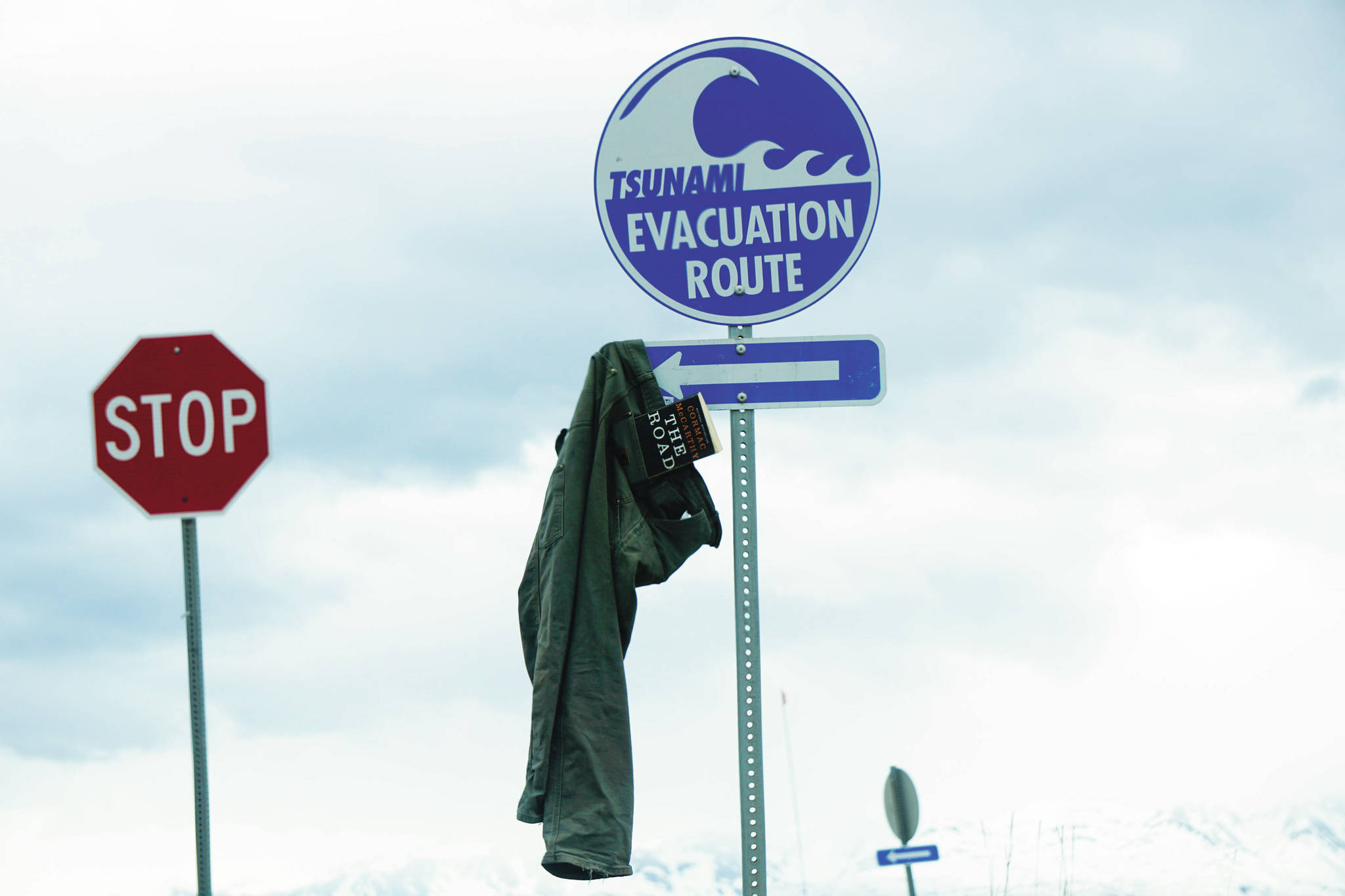 A pair of pants with a copy of Cormac McCarthy’s novel, “The Road,” hangs from a tsunami evacuation route sign on Saturday, May 8, 2021, at Mariner Park on the Homer Spit in Homer, Alaska. (Photo by Michael Armstrong/Homer News)
