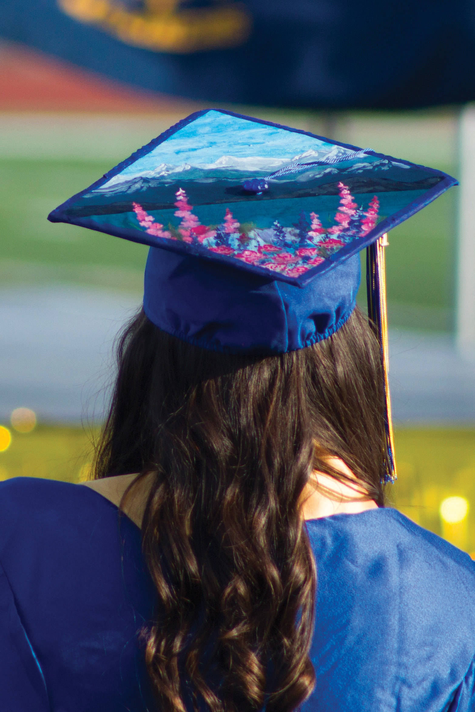 Photo by Sarah Knapp/Homer News 
A Homer High School graduate dons her graduation cap featuring Alaska scenery, including fireweed and the bay.