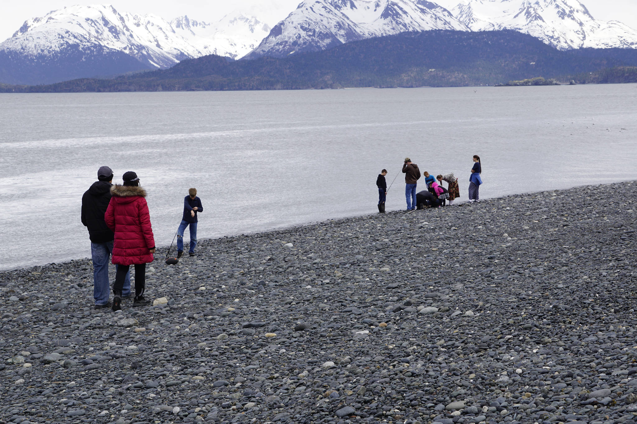 A couple walks along the beach, left, as a family fishes on Friday, May 21, 2021, at the end of the Homer Spit in Homer, Alaska. (Photo by Michael Armstrong/Homer News)