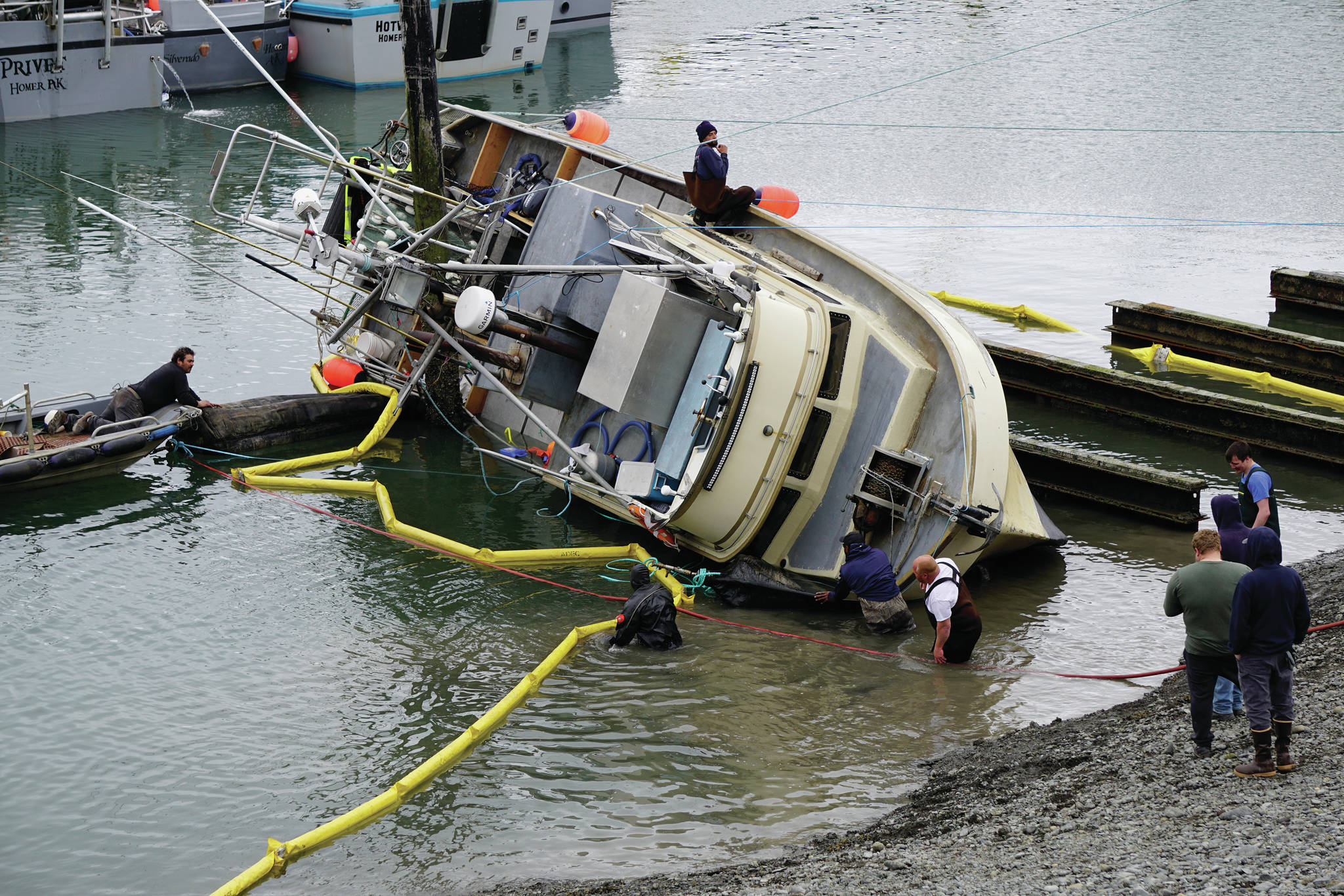 Workers respond to a fishing boat, the F/V Redoubt, that ran aground on the wooden grid on Wednesday, June 2, 2021, in the Homer Harbor in Homer, Alaska. The boat heeled over as the tide went out. (Photo by Michael Armstrong/Homer News)