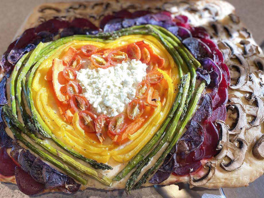 Photo by Tressa Dale/Peninsula Clarion 
Feta and Parmesan cheese, cherry tomatoes, carrot, yellow bell pepper, asparagus, purple potatoes, beets and white button mushrooms are shaped into a rainbow with a cheesy heart on top of focaccia bread.