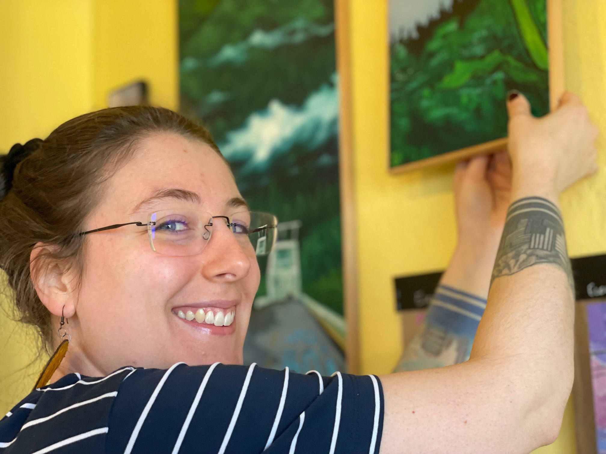 Homer artist Jenna Gerrety straightens paintings currently being shown at Sustainable Wares. (Photo by McKibben Jackinsky)