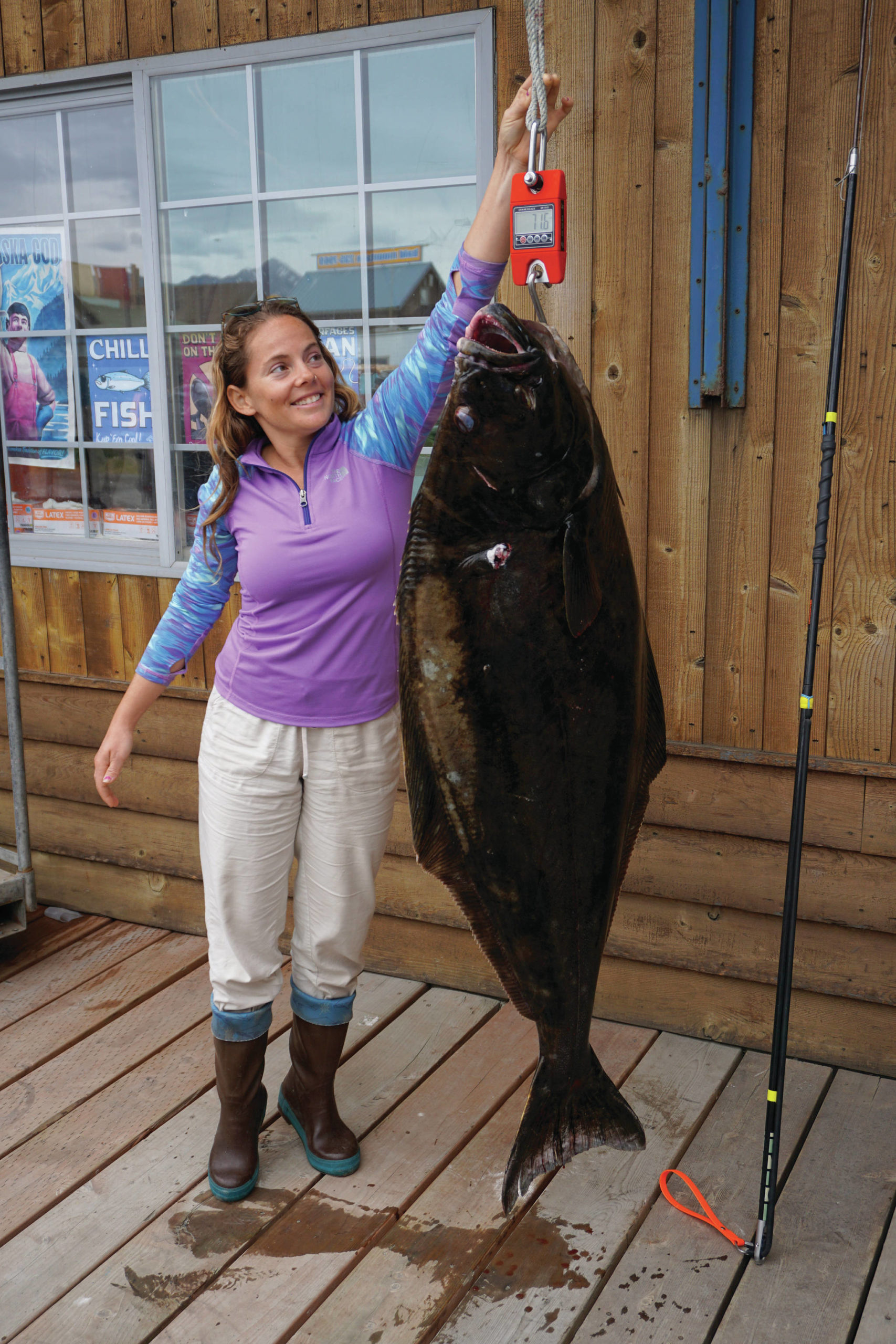 Lisa Stengel of Fort Lauderdale, Florida, weighs a halibut on Monday, July 12, 2021, at Coal Point Seafoods in Homer, Alaska, that she caught with a pole spear while free diving in Kachemak Bay. If verified, the 71.4-pound halibut would be the International Underwater Spearfishing Association world record for a Pacific halibut caught by a woman using a pole spear. (Photo by Michael Armstrong/Homer News)