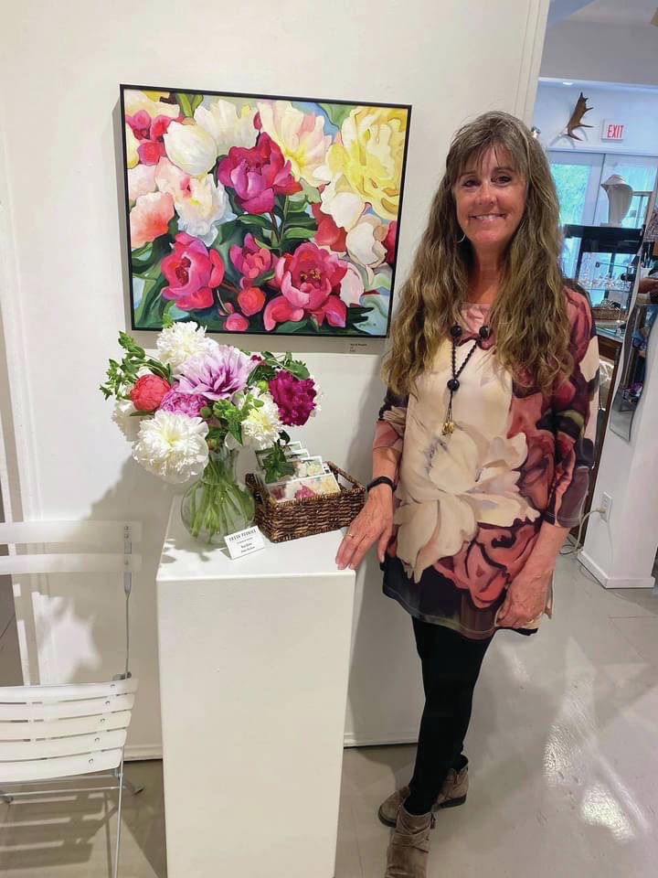 Gerri Martin poses with her show, "Peonies: Alaska's Floral Gems," for First Friday, July 2, 2021, at Fireweed Gallery in Homer, Alaska. (Photo courtesy of Gerri Martin)
