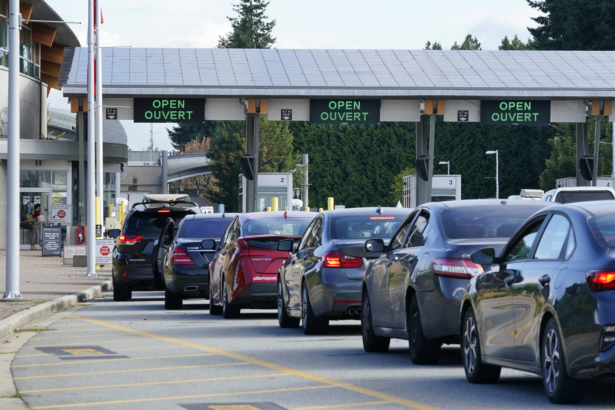 A line of vehicles wait to enter Canada at the Peace Arch border crossing Monday, Aug. 9, 2021, in Blaine, Wash. Canada lifted its prohibition on Americans crossing the border to shop, vacation or visit, but America kept similar restrictions in place, part of a bumpy return to normalcy from coronavirus travel bans. (AP Photo/Elaine Thompson)