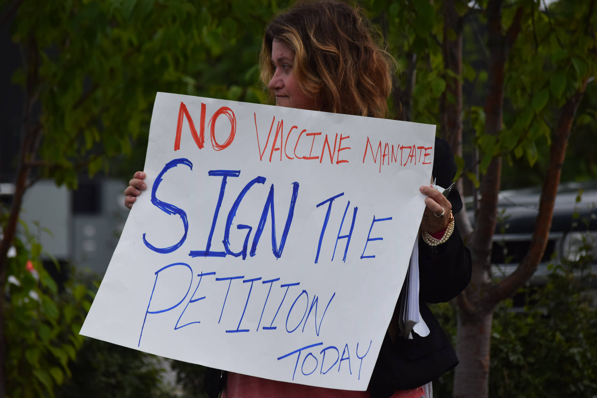 A demonstrator stands at the “Y” intersection of the Kenai Spur and Sterling highways in Soldotna on Saturday, Aug. 14 to protest mandatory COVID-19 vaccines and mitigation protocols. (Camille Botello/Peninsula Clarion)