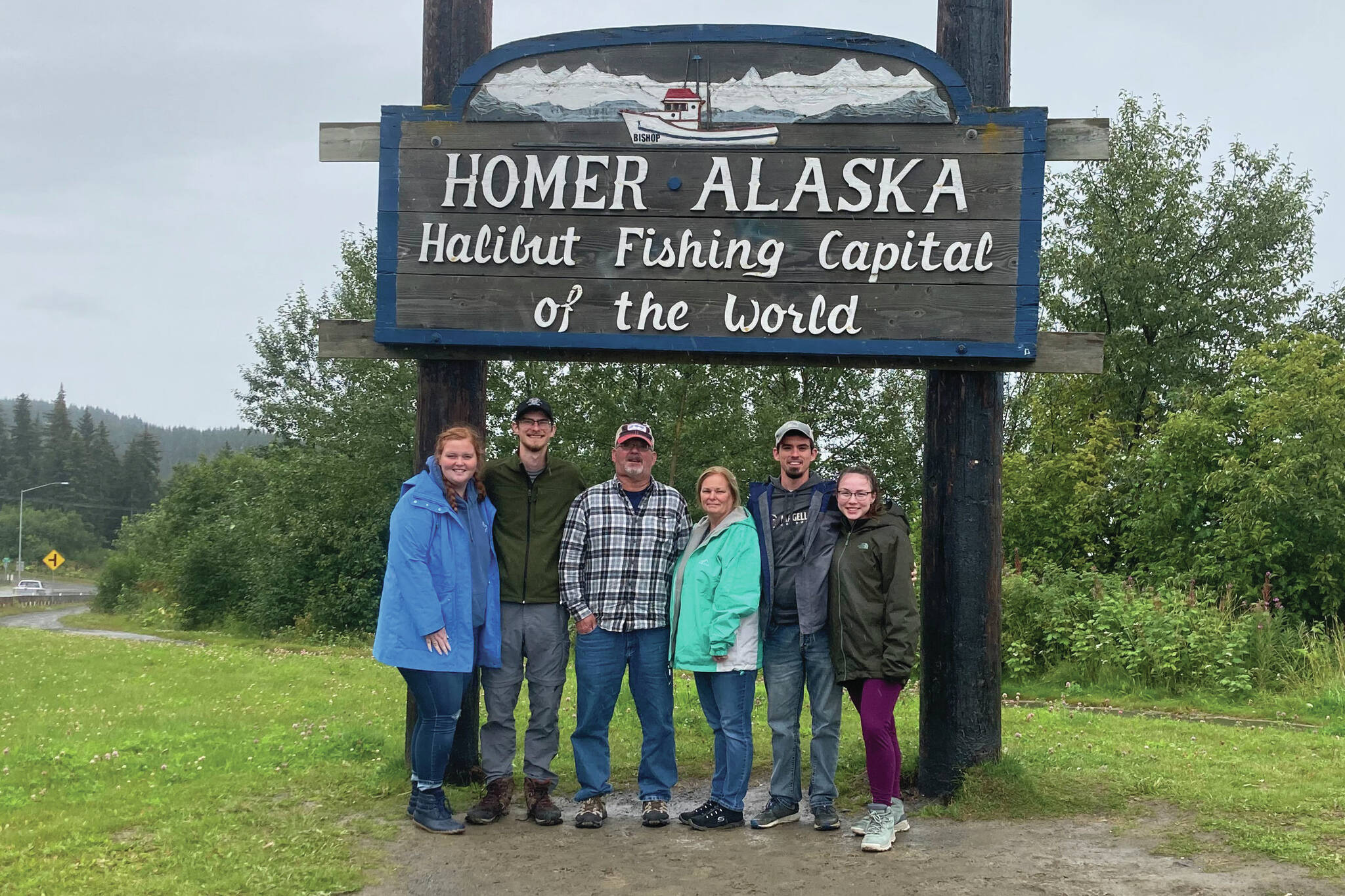 Sarah, Michael, Pete, Becky, Will and Margaret take a family picture in front of the Homer welcome sign on Baycrest.