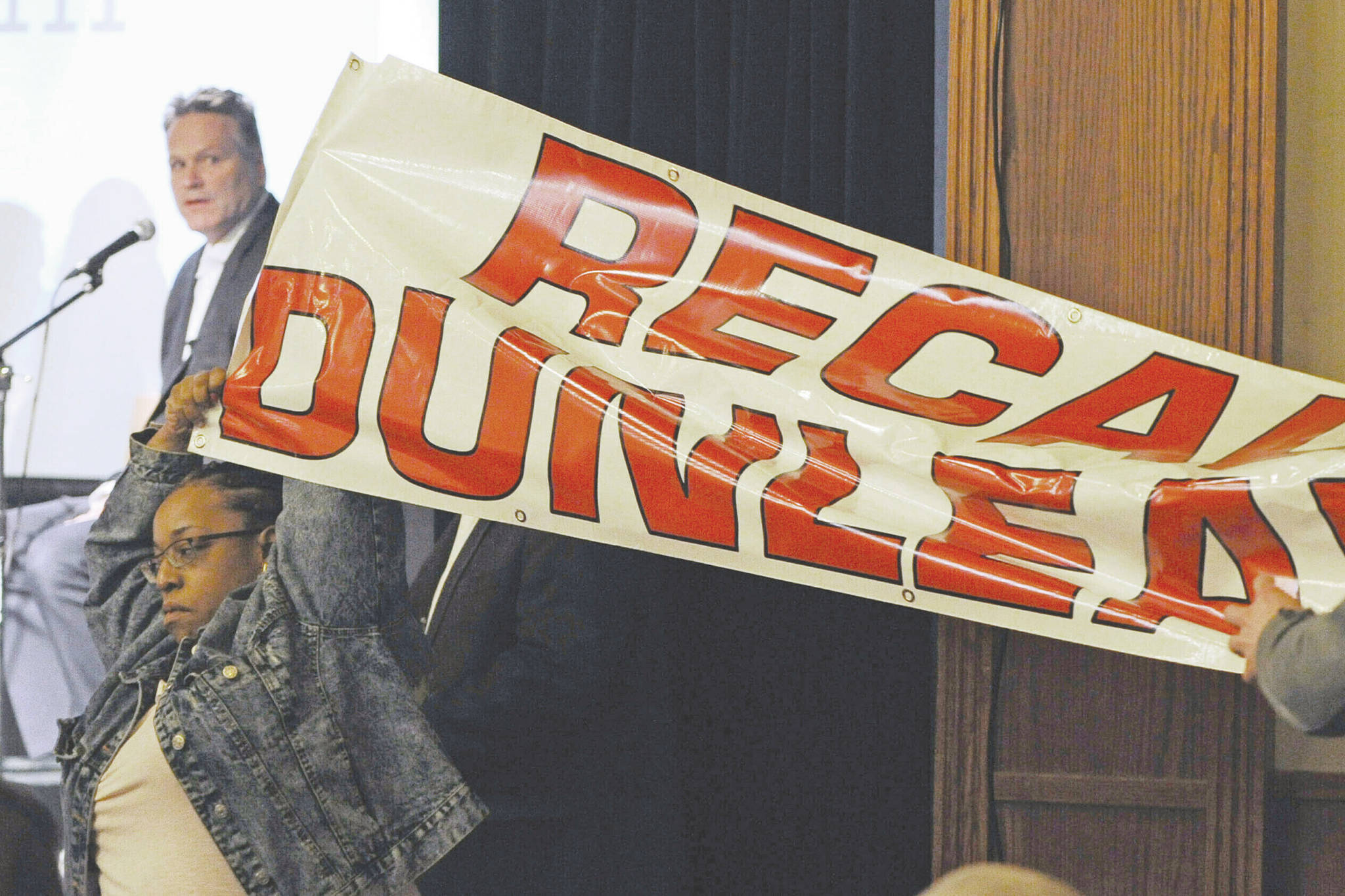 FILE - In this March 26, 2019, file photo, protestors unfurl a "Recall Dunleavy" banner as Gov. Mike Dunleavy, upper left, speaks during a roadshow with Americans for Prosperity in 49th State Brewing Company in Anchorage, Alaska. Dunleavy said he hopes to move past the rancor of his first year in office, amid an unsettled dispute with lawmakers over state spending and threat of a recall effort looming large. The Republican will mark a full year in office Tuesday, Dec. 3. (Bill Roth/Anchorage Daily News via AP, File)