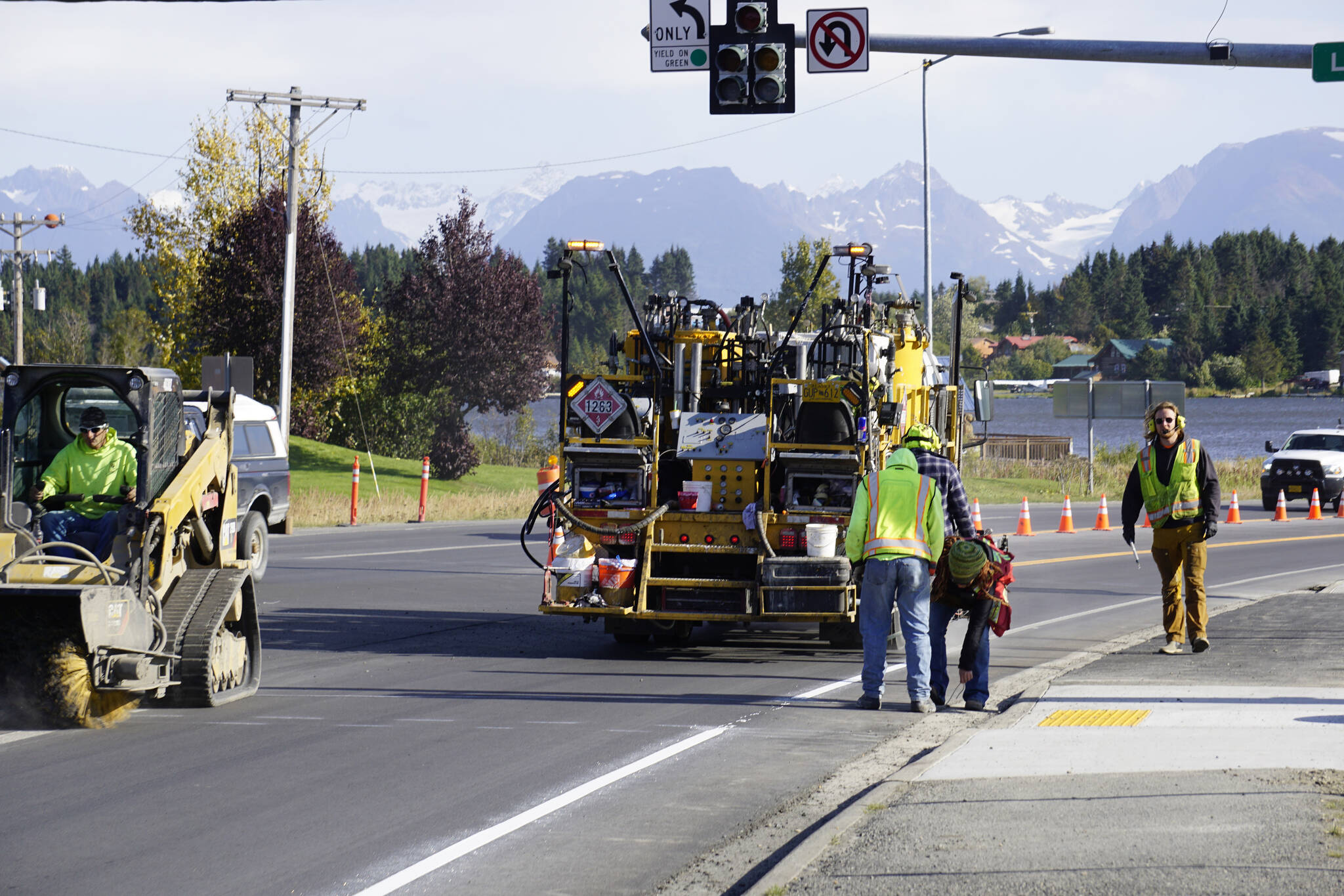 Workers on Tuesday, Sept. 21, 2021, paint the fog or right side lane lineon the Homer Bypass at Lake Street as reconstruction winds down for the summer inHomer, Alaska. (Photo by Michael Armstrong/Homer News)