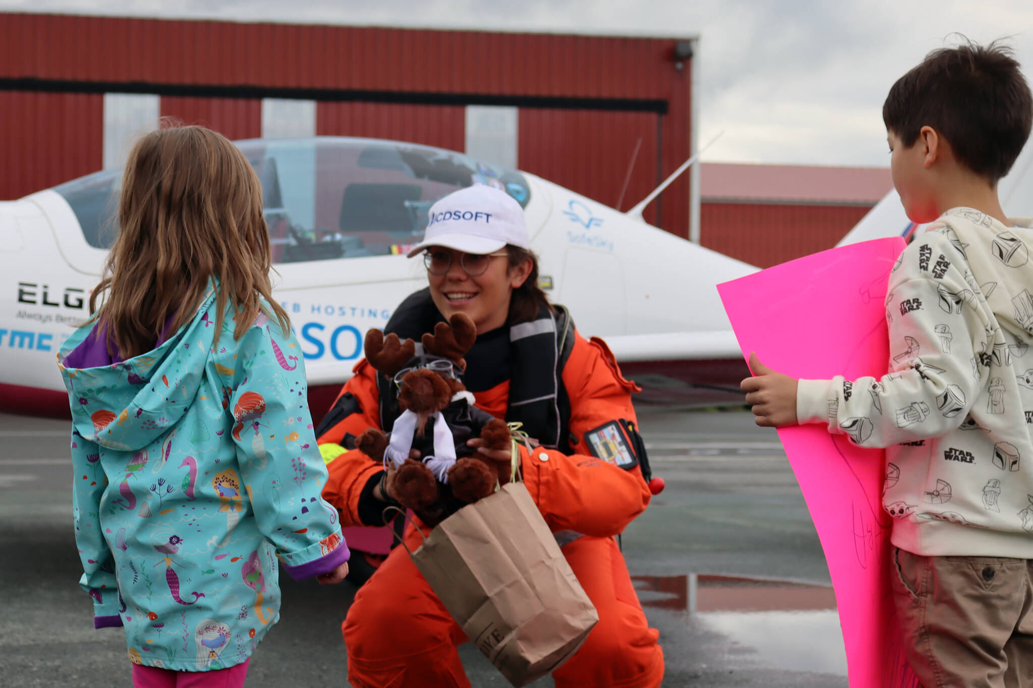 Amelia Conrad, 4, presents Zara Rutherford with a stuffed moose donning aviator goggles while Mclain Patterson, 7, holds a sign reading “Fly Zara Fly!” at Ward Air. Rutherford is flying her way around the world in pursuit of the Guinness world record for youngest woman solo pilot to circumnavigate the world. (Ben Hohenstatt / Juneau Empire)