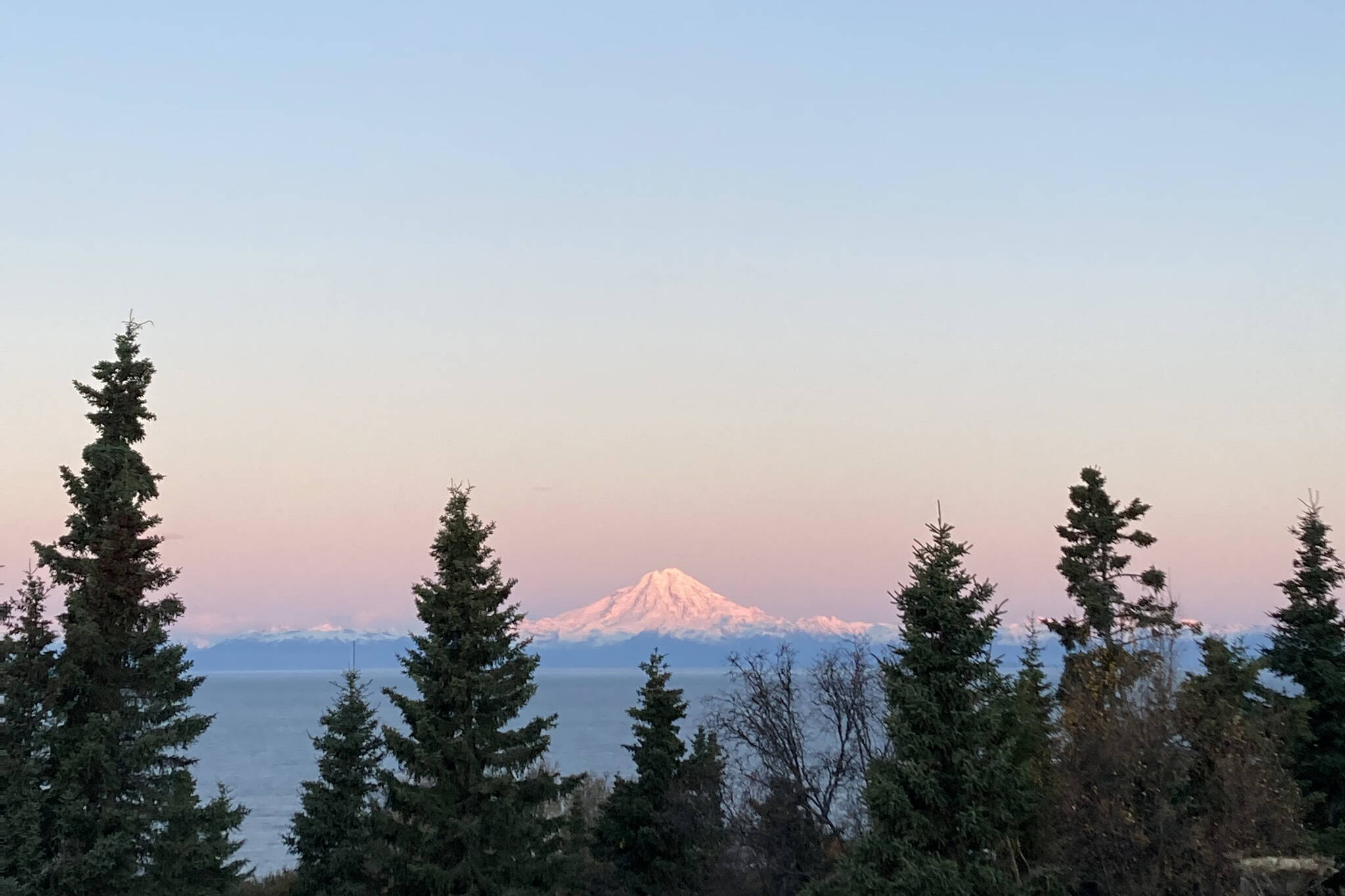 The sunrise shines on Mt. Redoubt Sunday, Oct. 10, creating hues of pinks, yellows and blues as it lights up the sky. (Photo by Sarah Knapp/Homer News)