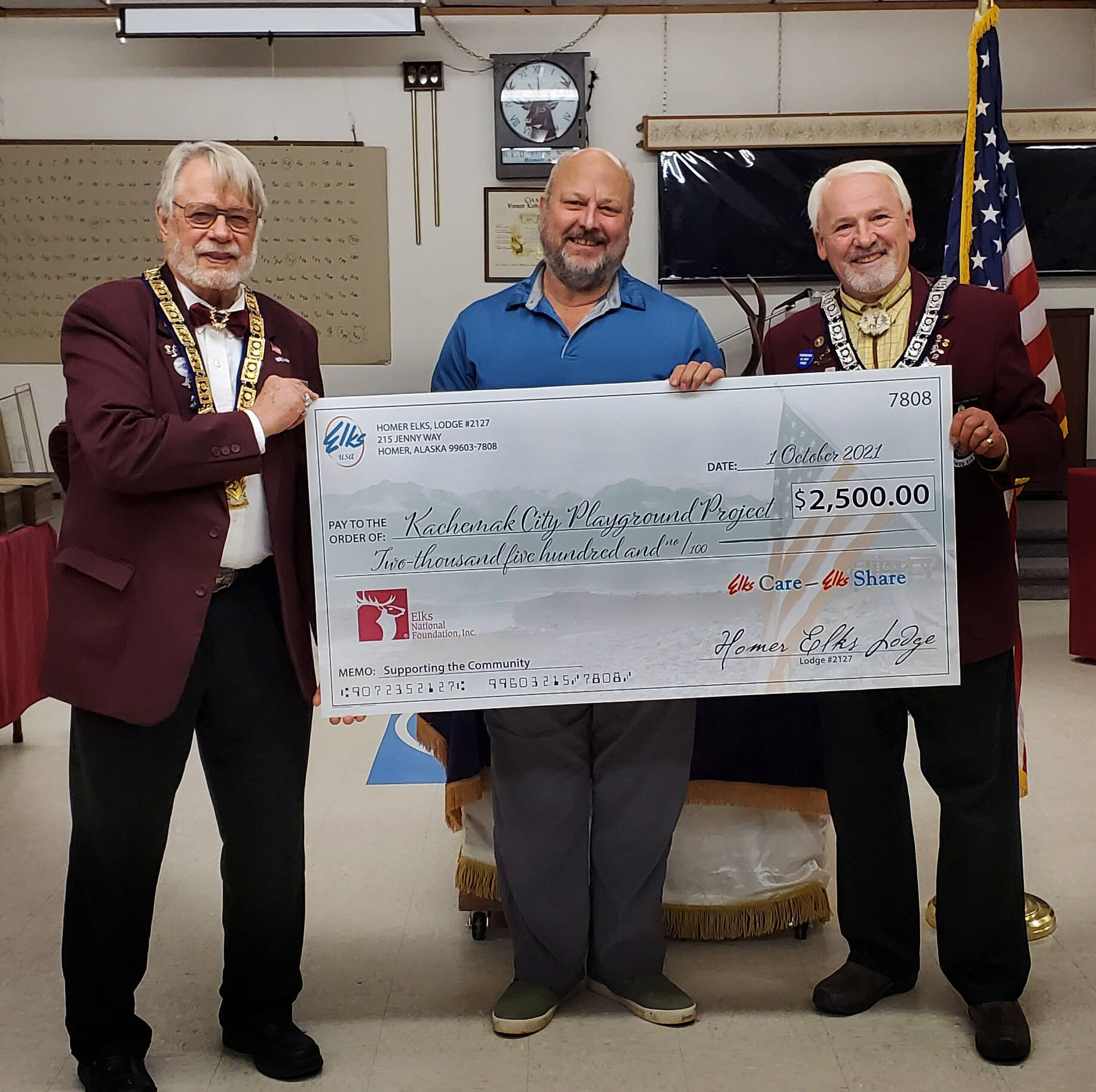 Homer Elks Lodge President David Spell, left, and Homer Elks Lodge Grant Coordinator Tom Stroozas, far right, present a $2,500 check to Kachemak City Council member Bill Fry, center, to help with construction of the Kachemak City Playground Project. (Photo provided)